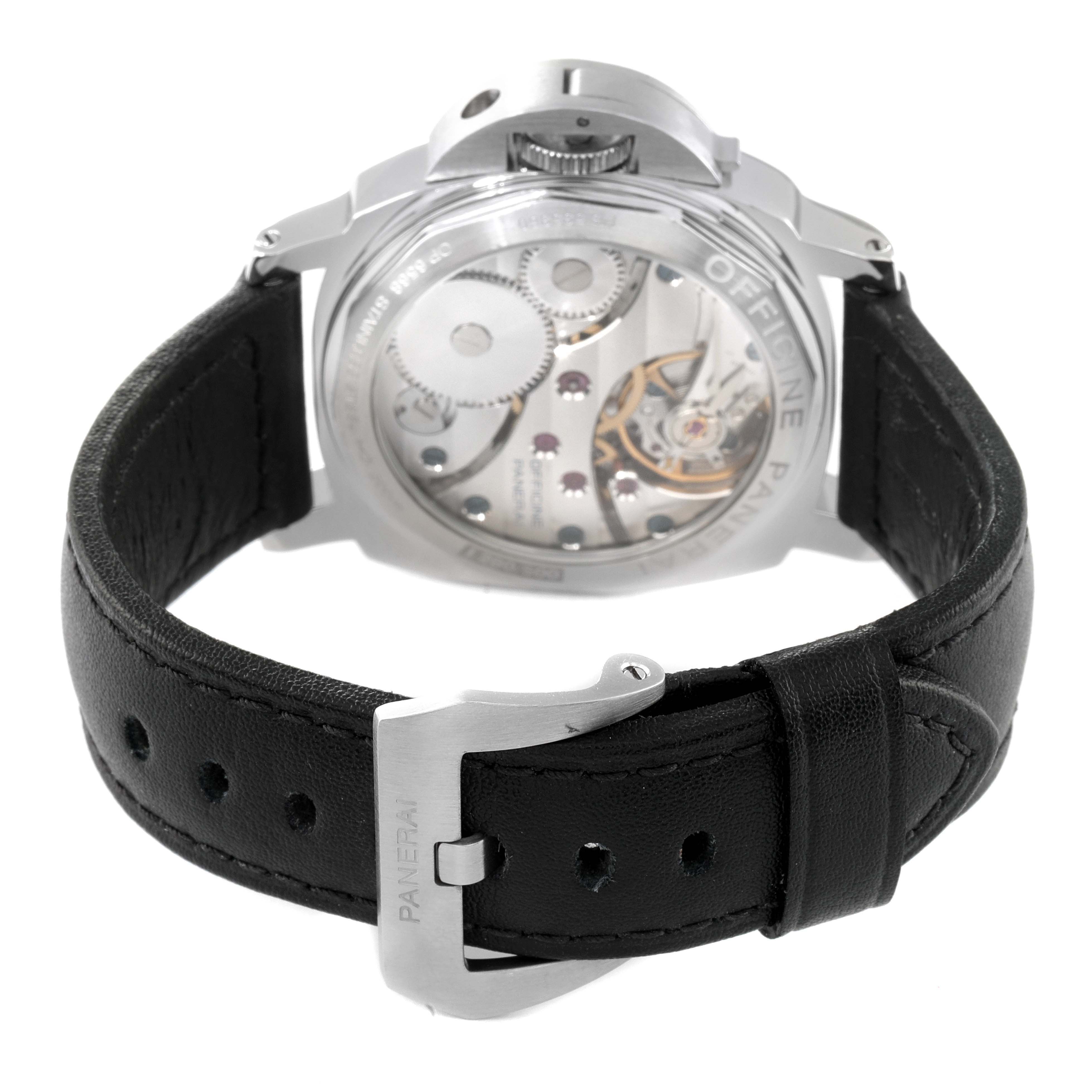 The image shows the back view of a Panerai Luminor PAM00114 Men
s Stainless Steel White Dial PAM00114 Men
s Stainless Steel White Dial watch, highlighting its movement and black leather strap with a signed buckle.