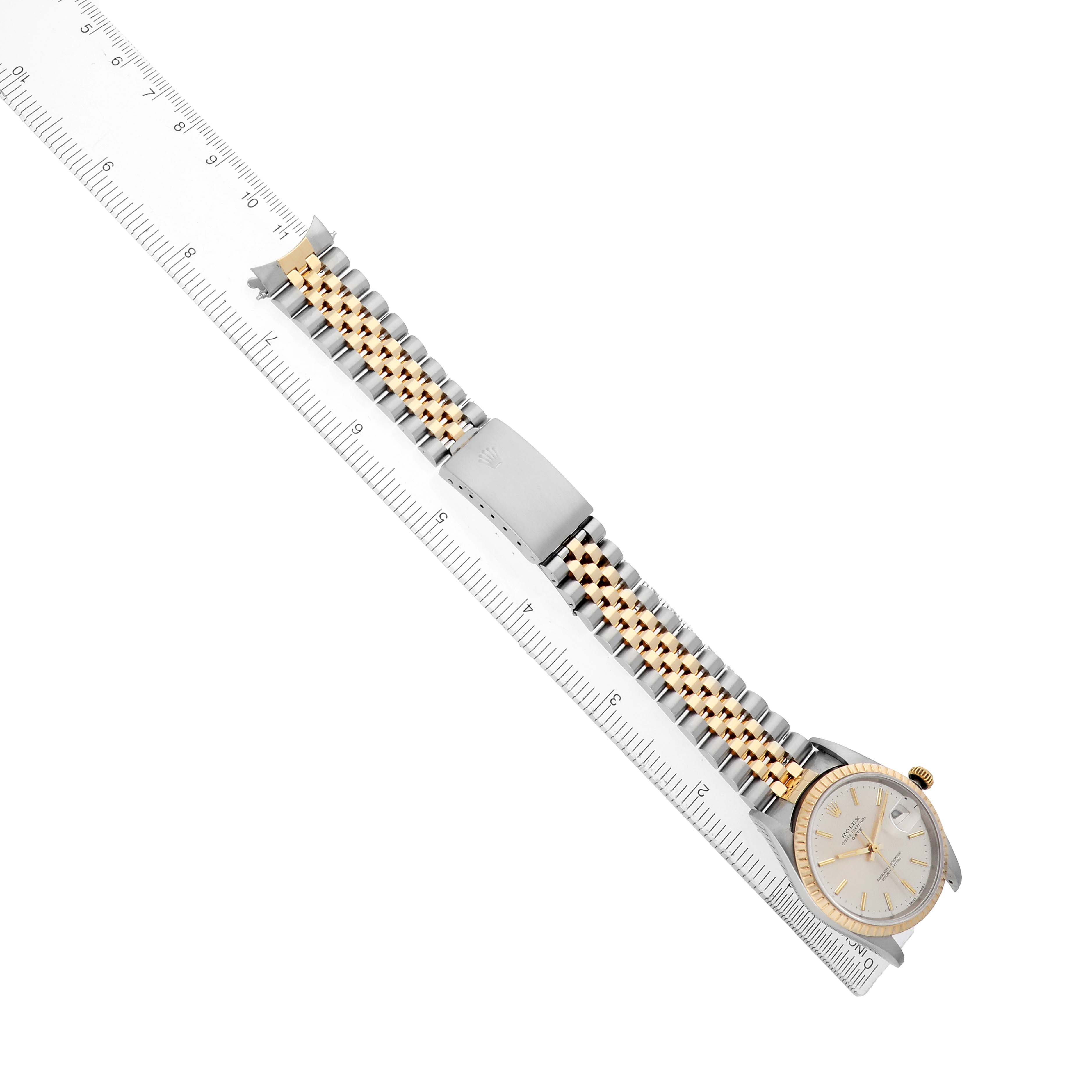 The Rolex Date 15223 Men's Steel and Gold (two tone) Silver Dial watch is shown from a top view, displaying the full bracelet, bezel, and dial alongside a ruler for scale.