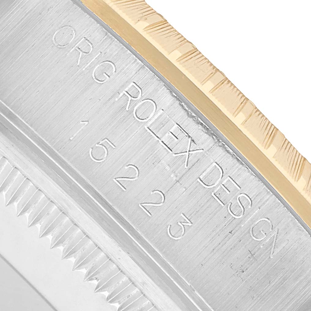 The image shows a close-up of the side of a Rolex Date 15223 Men's Steel and Gold (two tone) Silver Dial model, highlighting the engraved serial number and bezel.