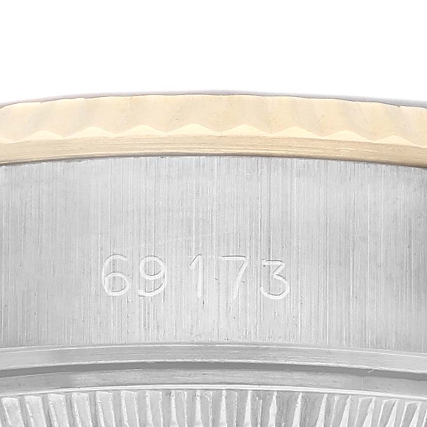 The image shows a close-up of the side of a Rolex Datejust 69173 Women's Steel and Gold (two tone) Champagne Dial watch, focusing on the bezel and engraved case number.