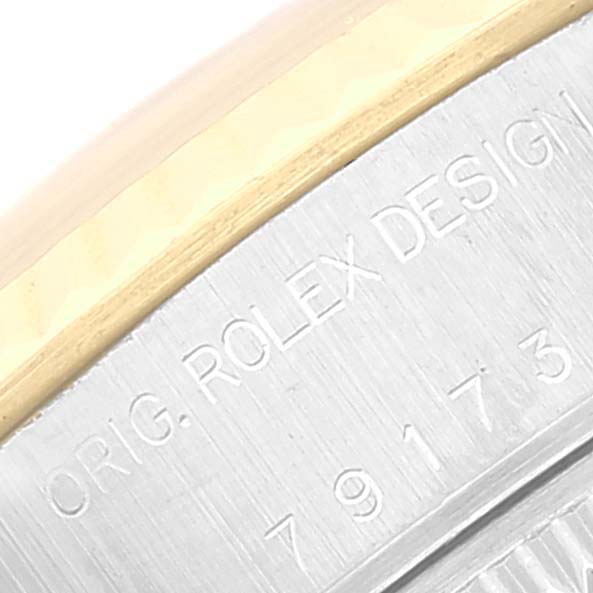 The image shows a close-up of the case back edge of a Rolex Datejust 79173 Women's Steel and Gold (two tone) White Dial 79173 Women's Steel and Gold (two tone) White Dial, displaying part of the serial number and "ROLEX DESIGN" engraving.
