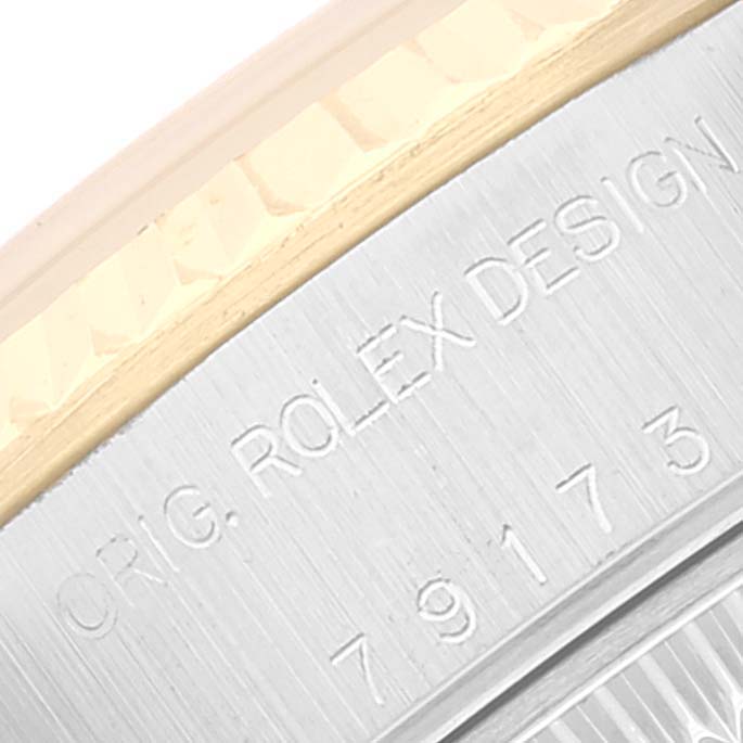 This image shows a close-up of the engraved text and fluted bezel on a Rolex Datejust 79173 Women's Steel and Gold (two tone) White Dial 79173 Women's Steel and Gold (two tone) White Dial watch.