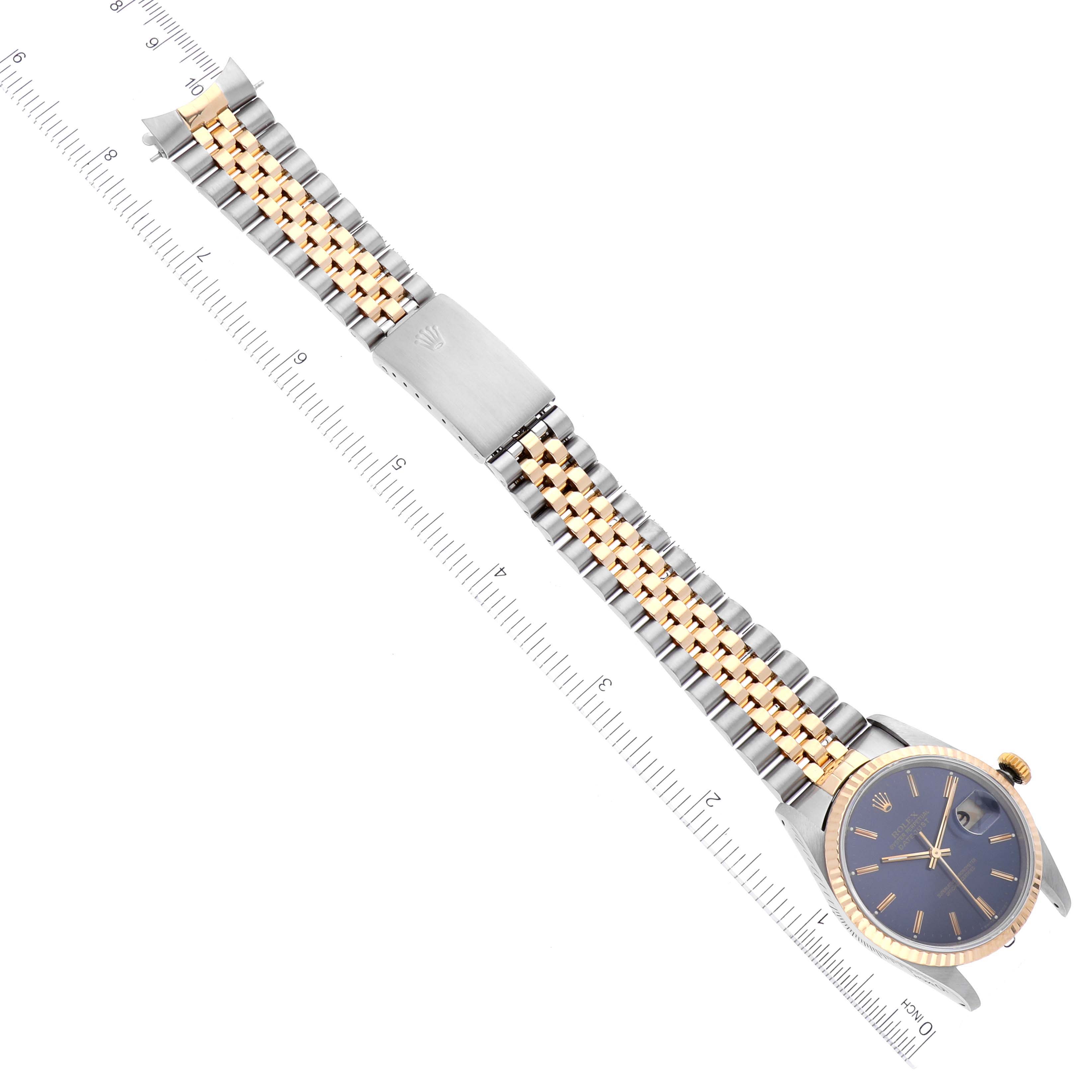 The Rolex Datejust 16233 Men's Steel and Gold (two tone) Blue Dial 16233 Men's Steel and Gold (two tone) Blue Dial watch is shown from a top-down angle, displaying its face and metal bracelet with a ruler for scale.