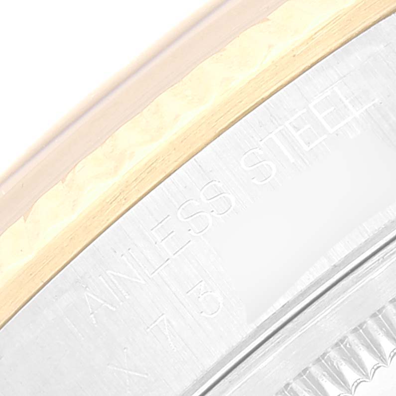 This close-up image of a Rolex Datejust 16233 Men's Steel and Gold (two tone) Blue Dial 16233 Men's Steel and Gold (two tone) Blue Dial watch shows part of the bezel and the edge of the case with "STAINLESS STEEL" engraved.