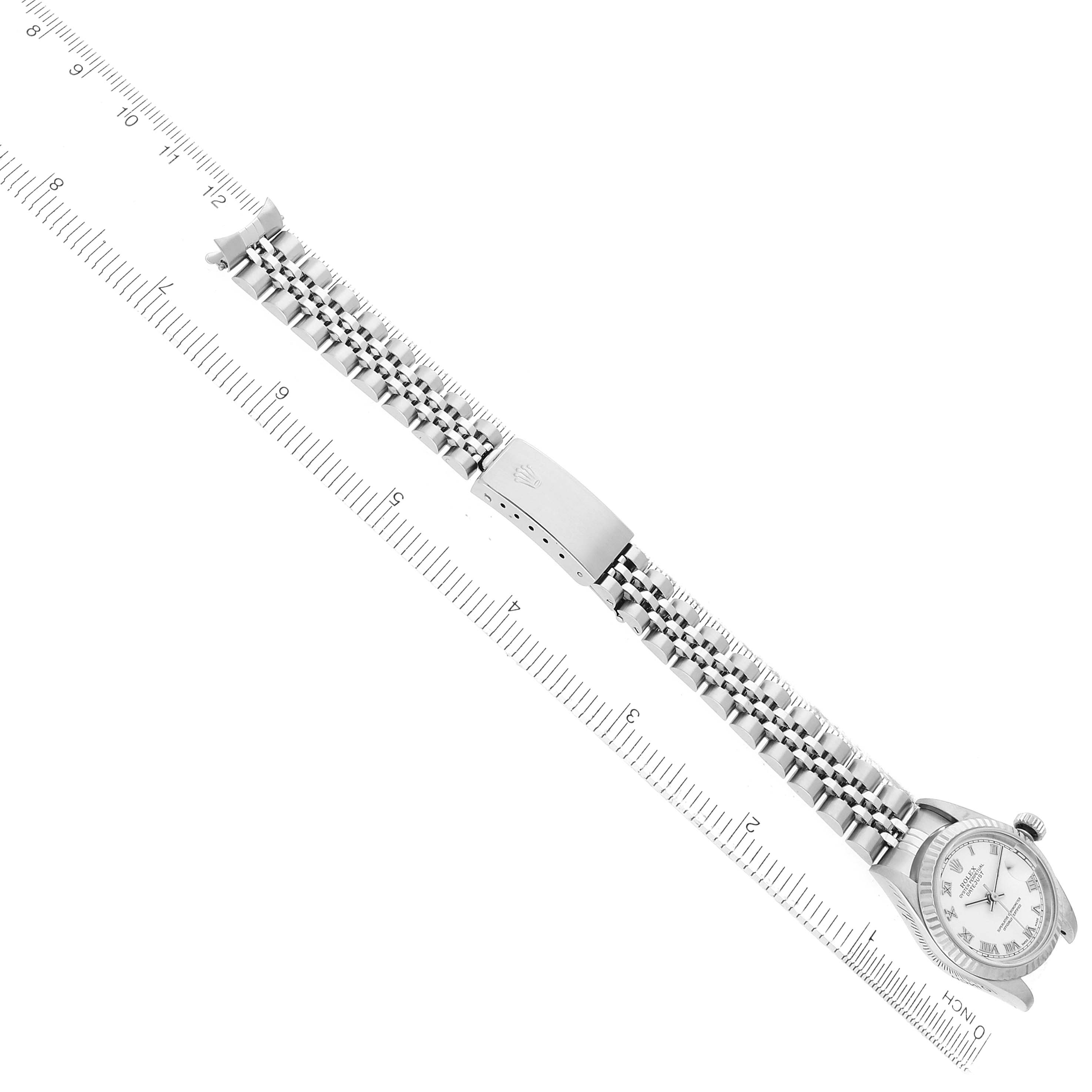 The image shows the Rolex Datejust 79174 Women's Stainless Steel White Dial watch from a top-down angle, highlighting the bracelet and clasp next to a ruler.