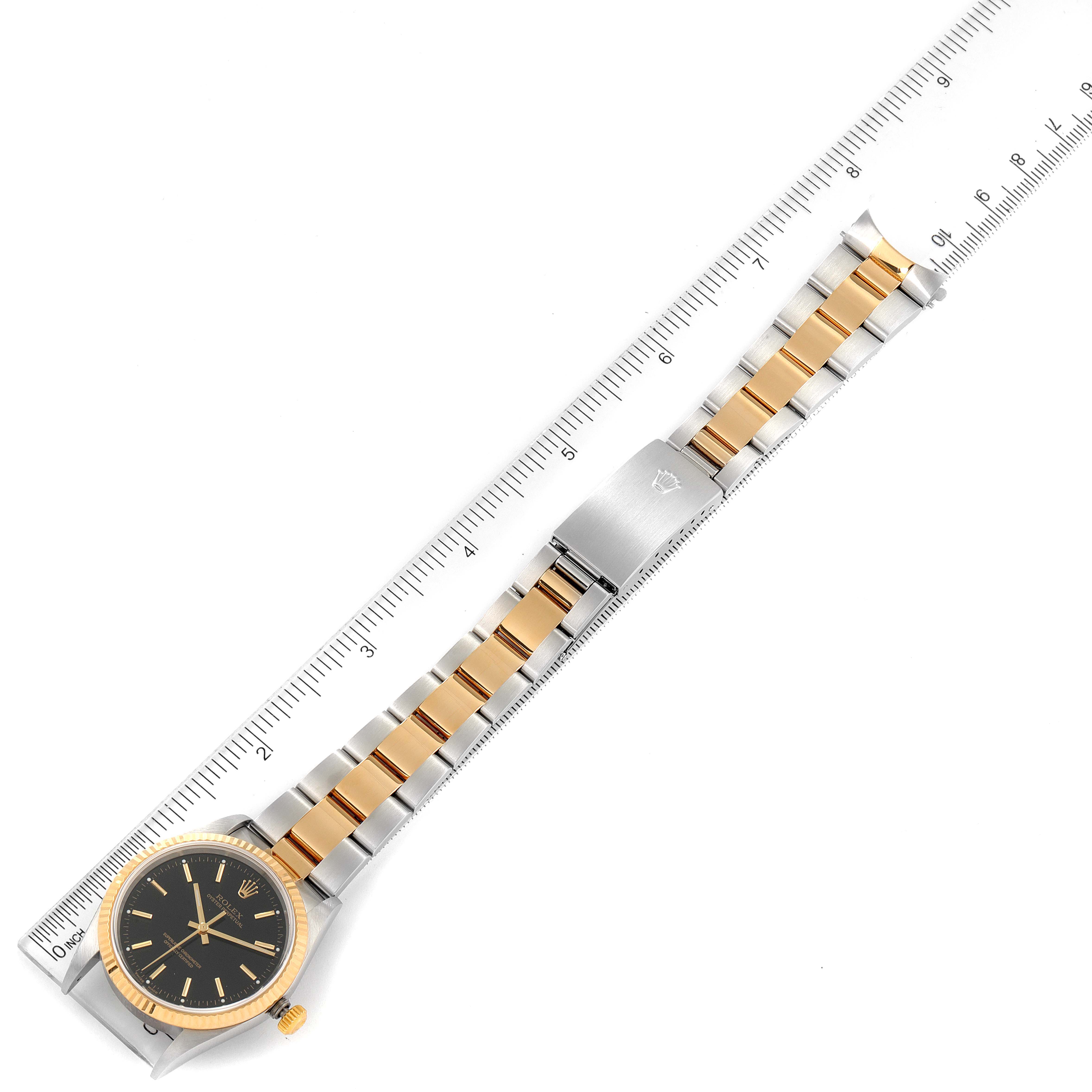 This image shows a Rolex Oyster Perpetual 14233 Men's Steel and Gold (two tone) Black Dial 14233 Men's Steel and Gold (two tone) Black Dial watch with a dual-tone band, aligned next to a ruler.