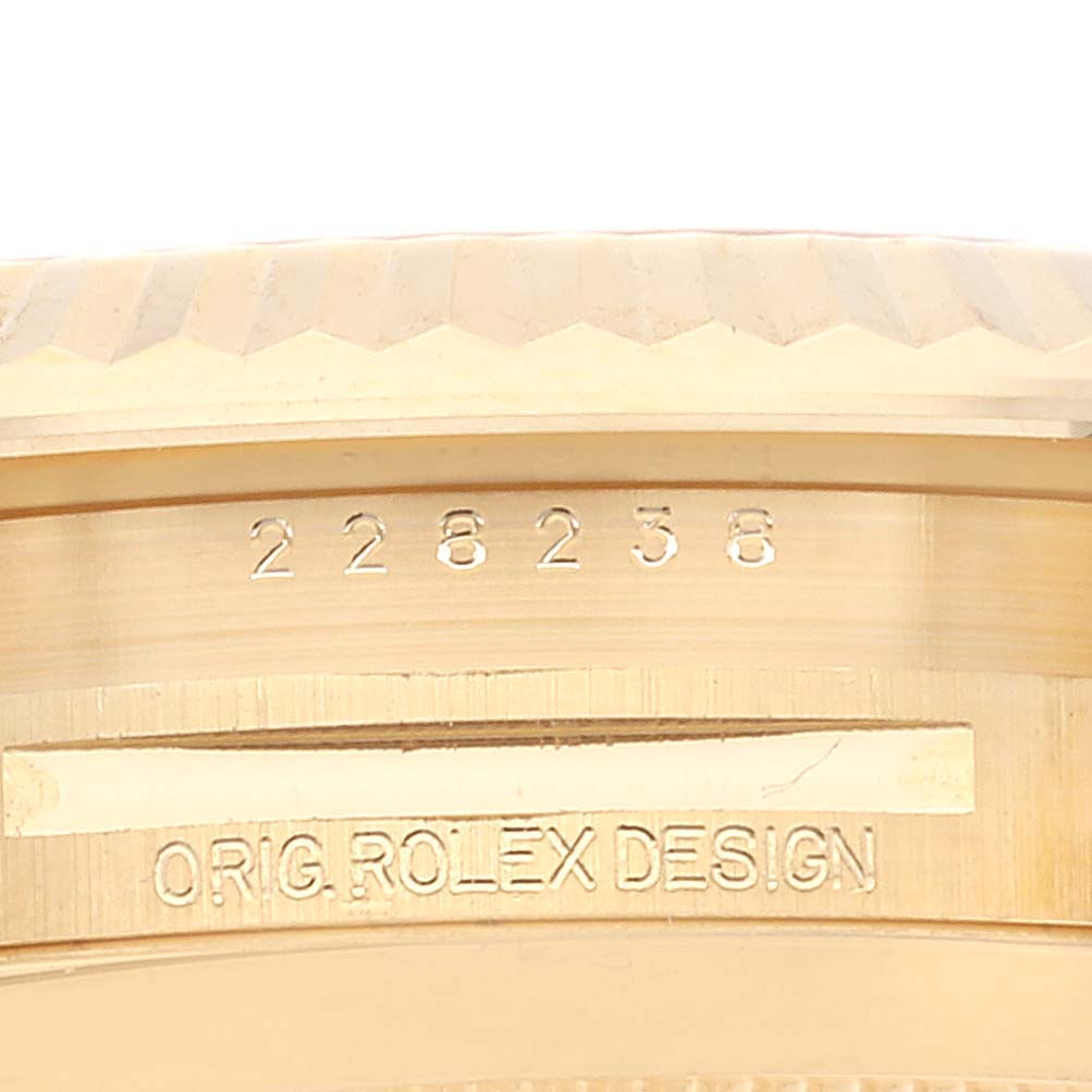 Close-up of a Rolex President 228238 Men's Yellow Gold Black Dial 228238 Men's Yellow Gold Black Dial model showing the crown, bezel edge, and engraved serial number and text.