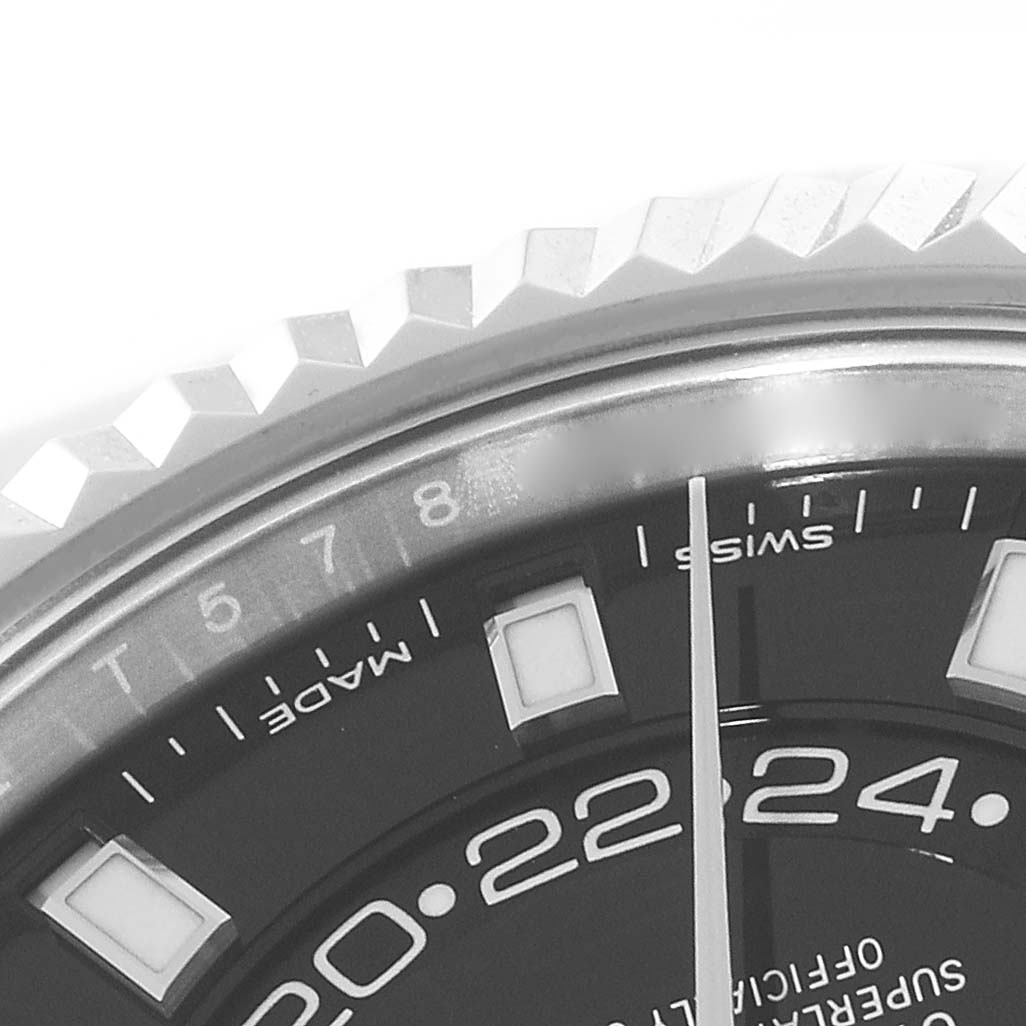 This close-up image of a Rolex Sky-Dweller 326934 Men
s Stainless Steel Black Dial 326934 Men
s Stainless Steel Black Dial watch shows part of the dial, including the hour markers, lettering, and part of the fluted bezel.