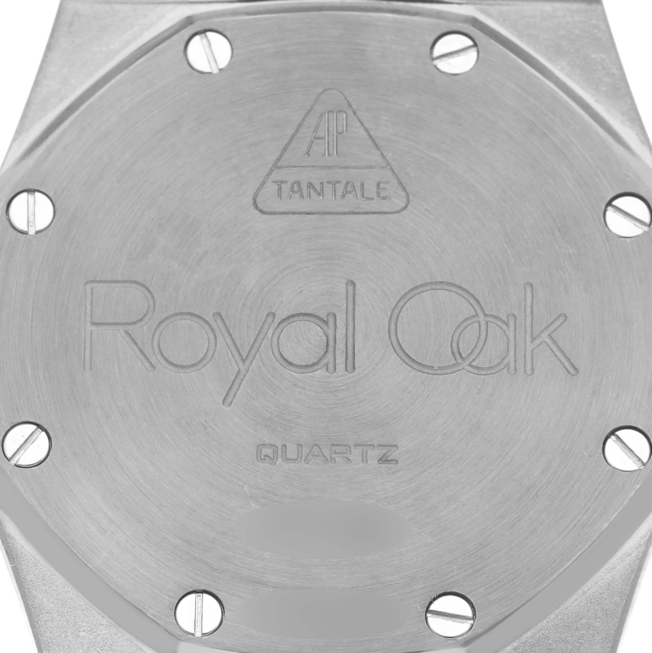 The image shows the back case of a Royal Oak by Audemars Piguet, featuring screws and engraved details.