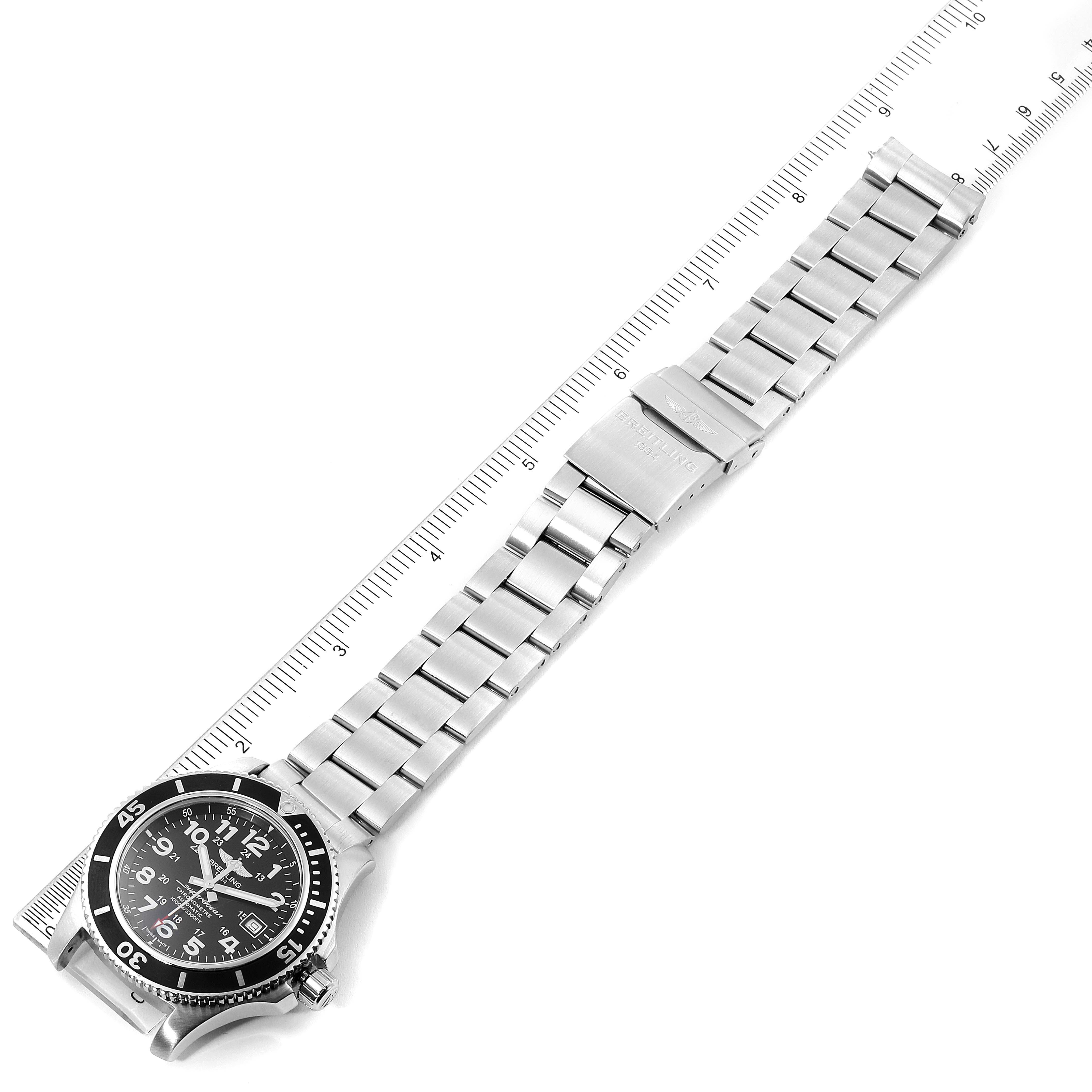 This image shows a Breitling Superocean A17392D8/C910 Men's Stainless Steel Black Dial A17392D8/C910 Men's Stainless Steel Black Dial watch laid flat, featuring its black dial and metal bracelet alongside a measurement ruler.