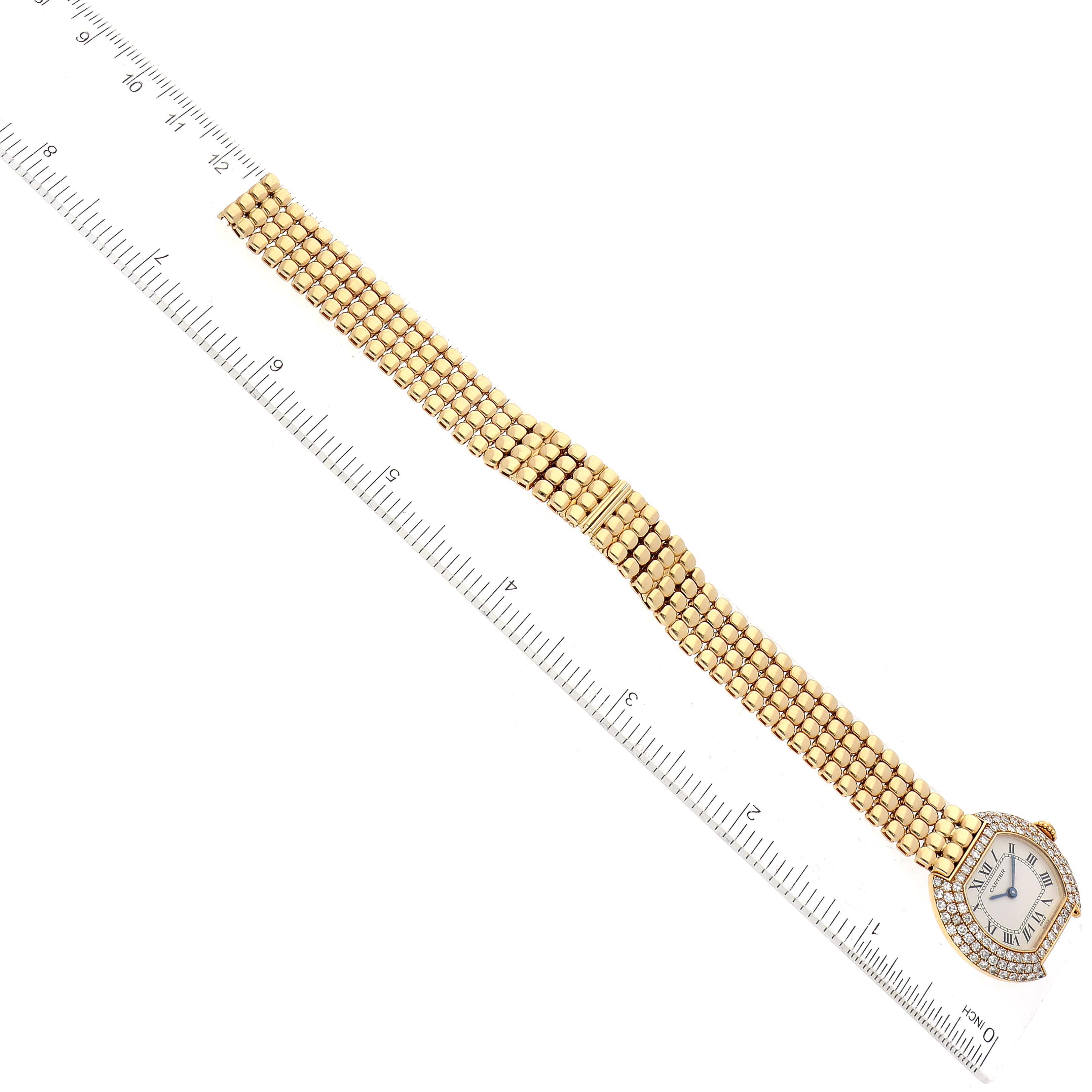The image shows a Cartier Tortue Women's Yellow Gold Silver Dial Women's Yellow Gold Silver Dial watch positioned next to a ruler, displaying the face and full length of the gold band.