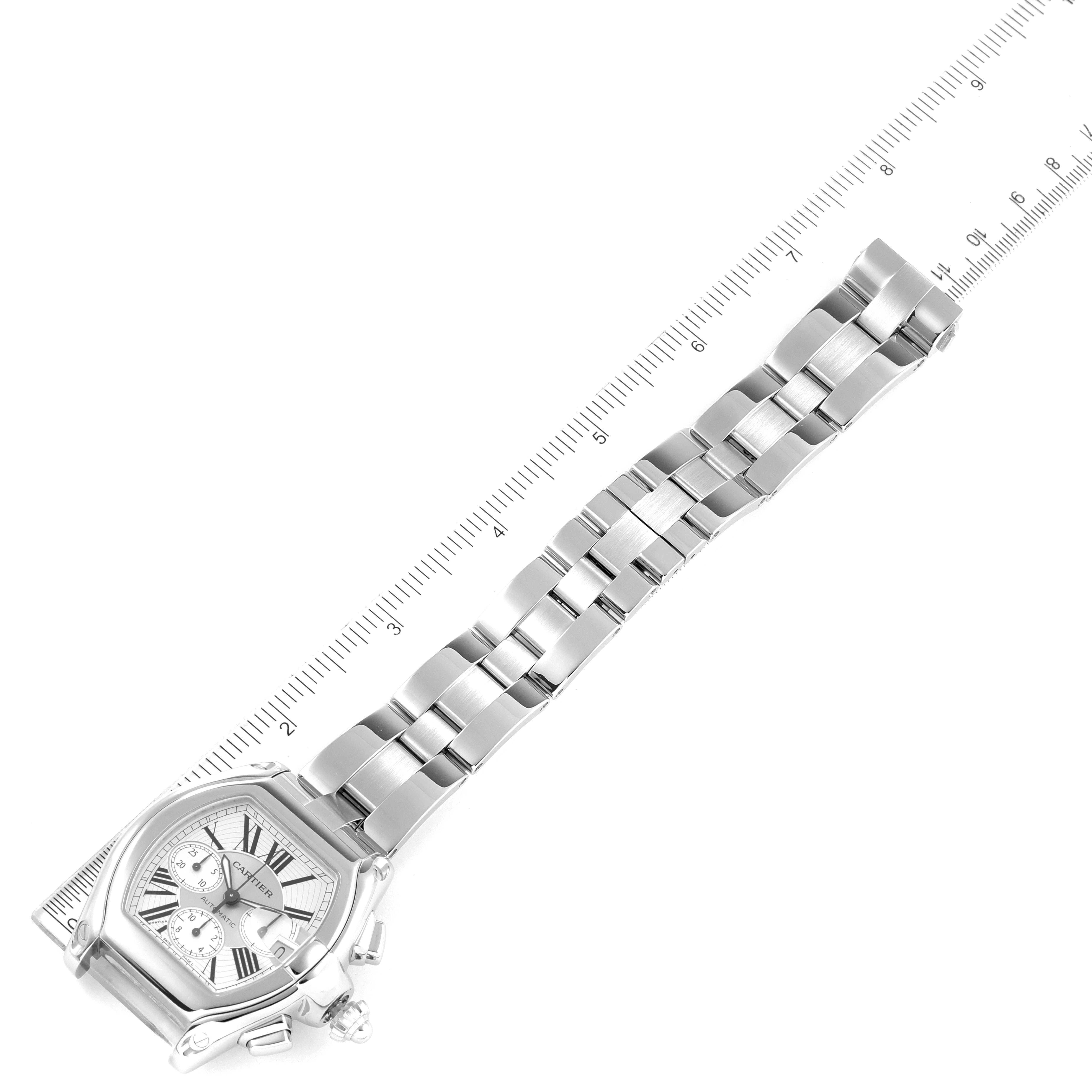 The image displays a Roadster model watch by Cartier from a top-down angle, showing the dial, crown, and the metal bracelet fully extended next to a ruler.