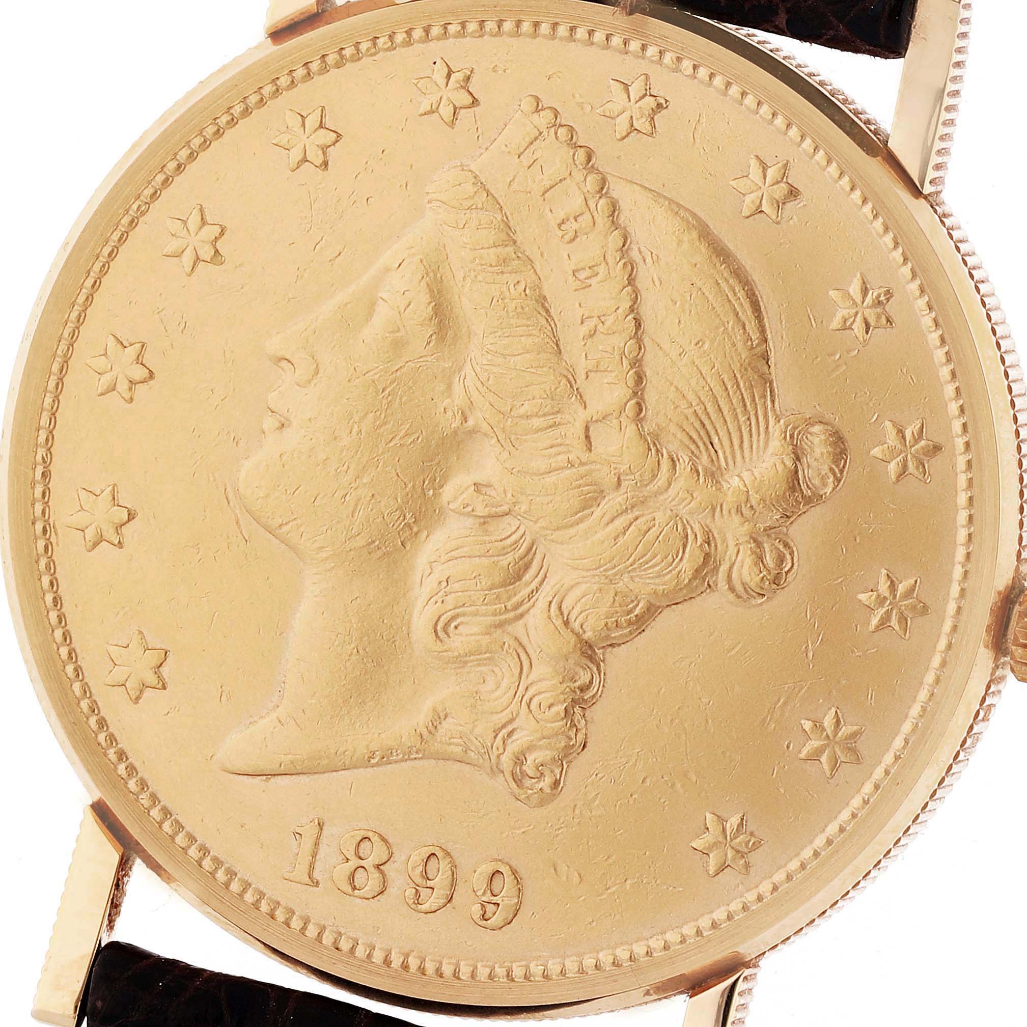 This image shows the face and part of the strap of the Corum Coin Watch 4414556 Men's Yellow Gold Champagne Dial 4414556 Men's Yellow Gold Champagne Dial model, displaying a detailed coin design with an 1899 date.