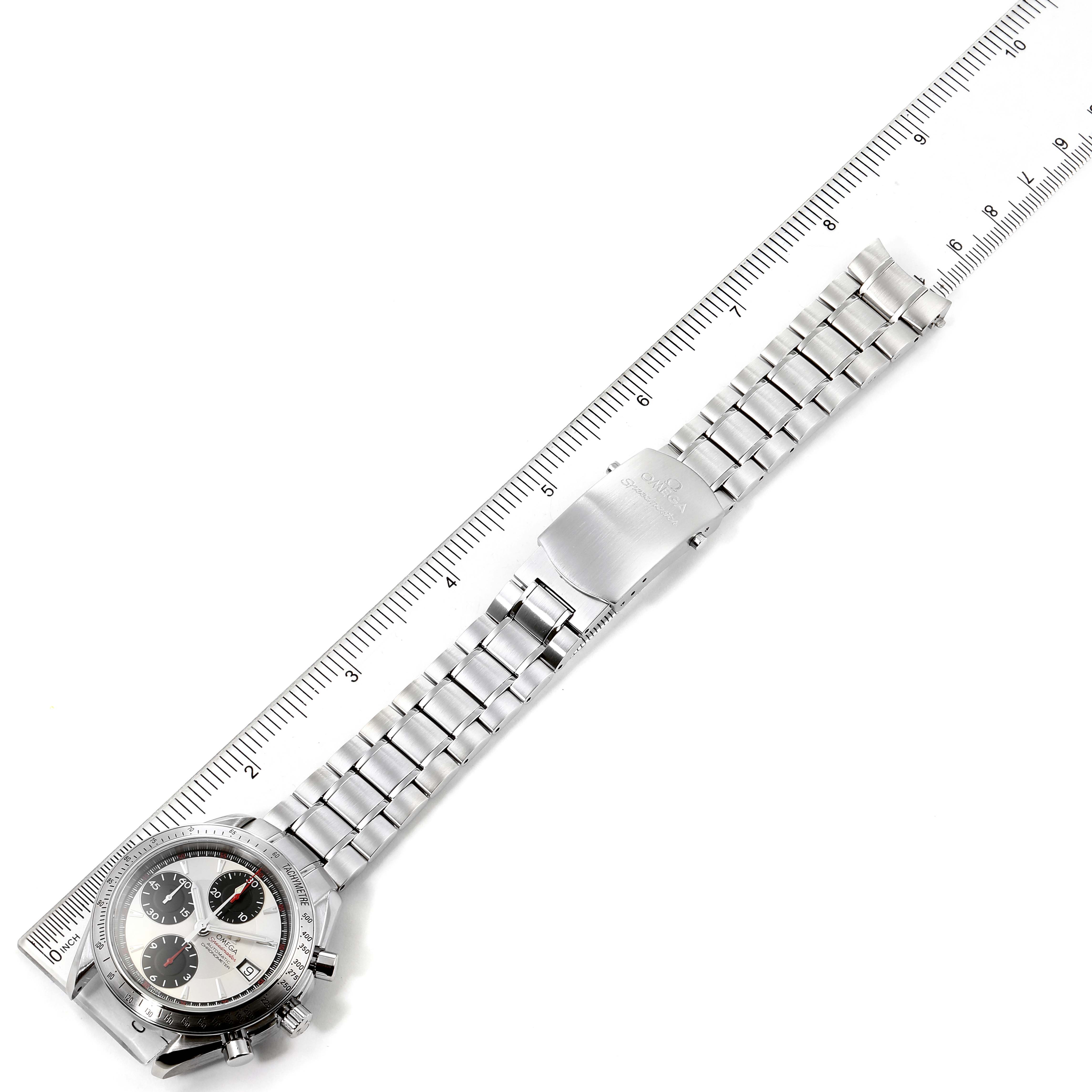 An Omega Speedmaster 3211.31.00 Men's Stainless Steel Silver Dial 3211.31.00 Men's Stainless Steel Silver Dial watch is shown laid flat with a ruler beside it, highlighting the bracelet and face.