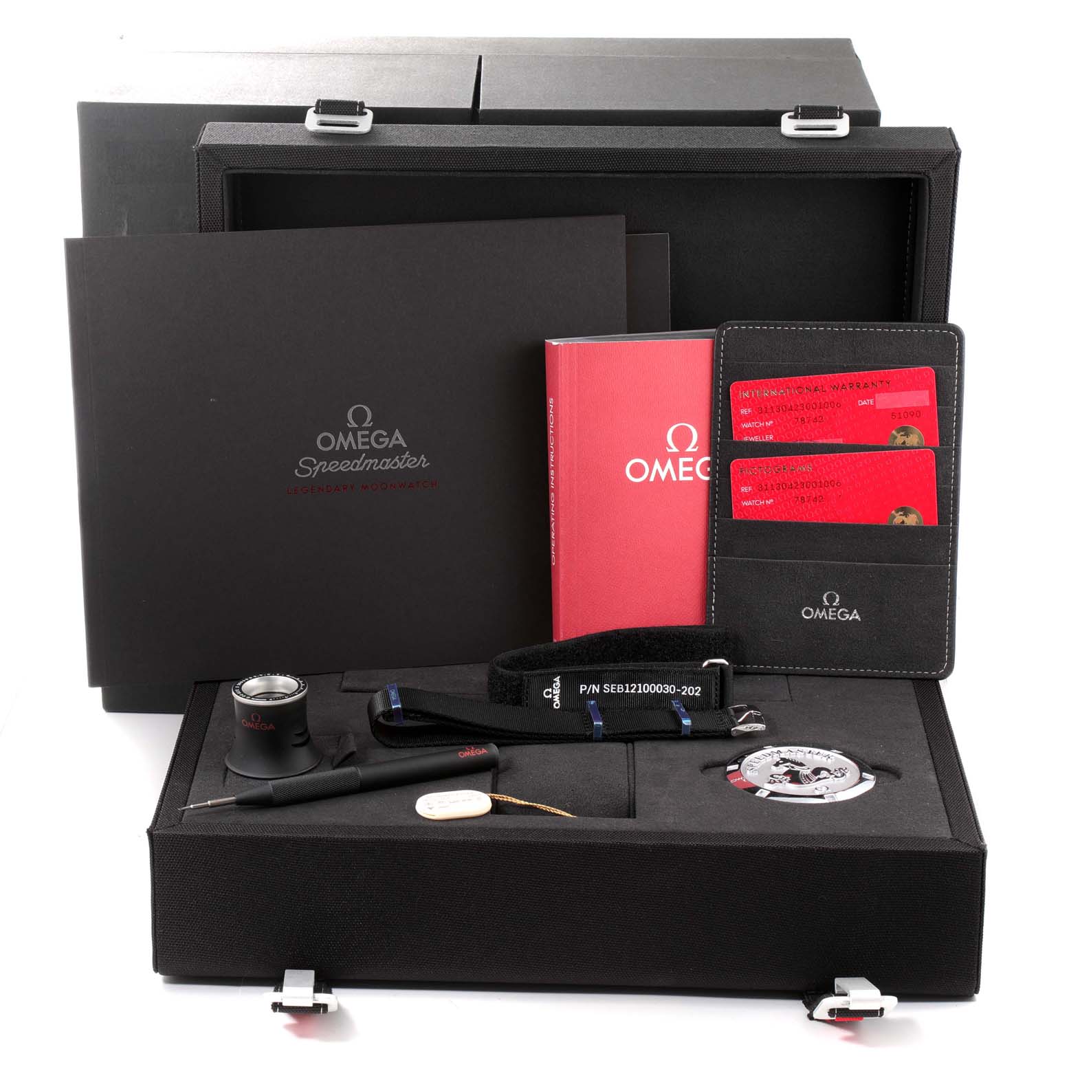 This image shows the accessories and packaging of the Omega Speedmaster 311.30.42.30.01.006 Men's Stainless Steel Black Dial 311.30.42.30.01.006 Men's Stainless Steel Black Dial, including a storage box, manuals, a magnifier, a strap, and tools.