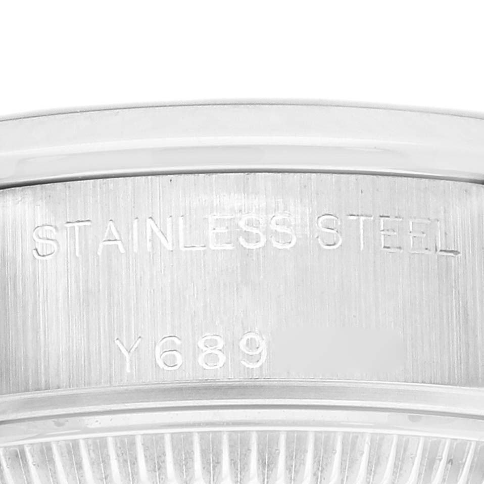 The image shows a close-up of the Date model by Rolex, focusing on the engraved stainless steel case back.