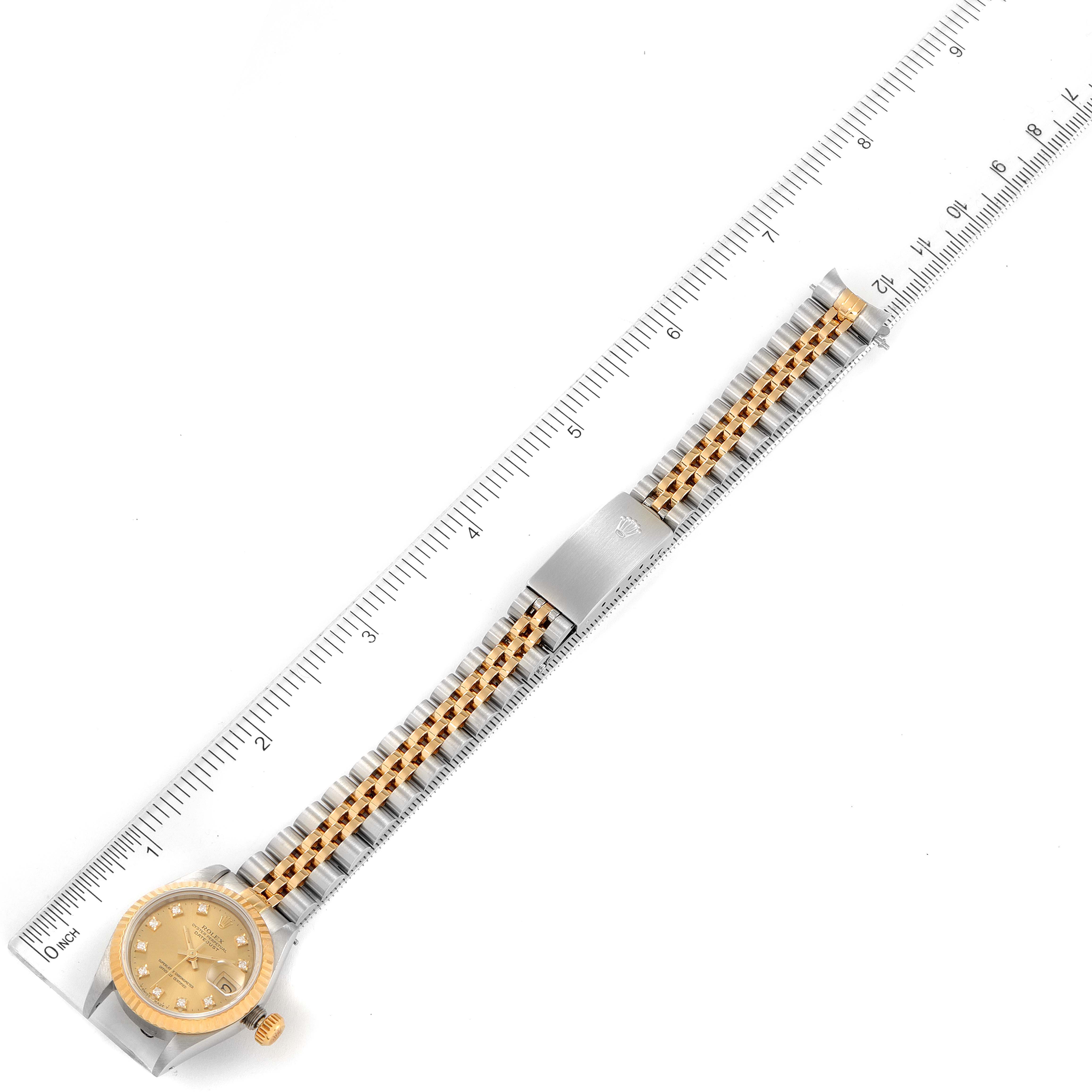 This image shows an overhead view of a Rolex Datejust 69173 Women
s Steel and Gold (two tone) Champagne Dial 69173 Women
s Steel and Gold (two tone) Champagne Dial watch, showcasing the entire bracelet, dial, and crown along with a ruler for scale.