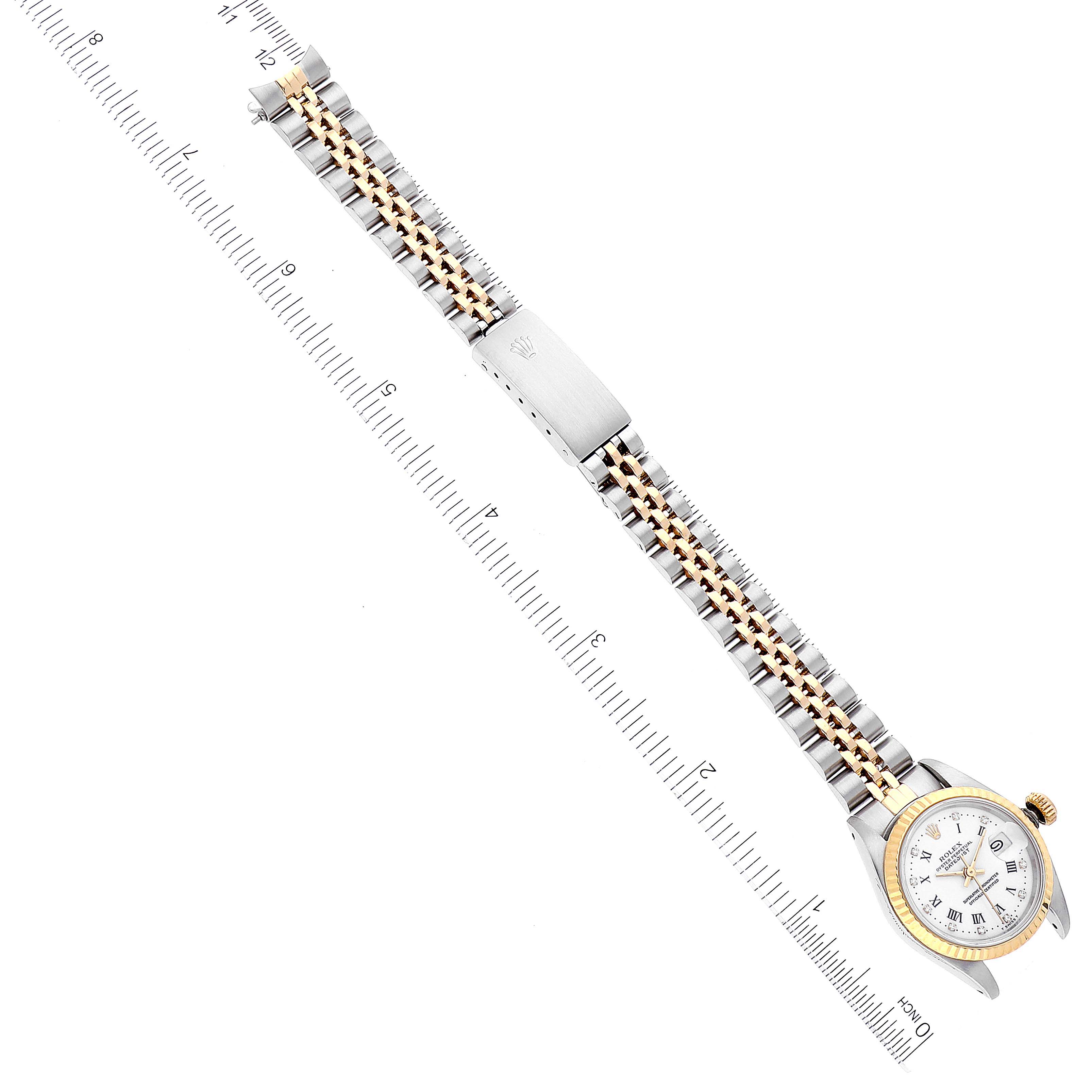 The image shows a top-down view of a Rolex Datejust 69173 Women's Steel and Gold (two tone) White Dial 69173 Women's Steel and Gold (two tone) White Dial watch, displaying its dial, bezel, and metal bracelet against a measuring ruler.