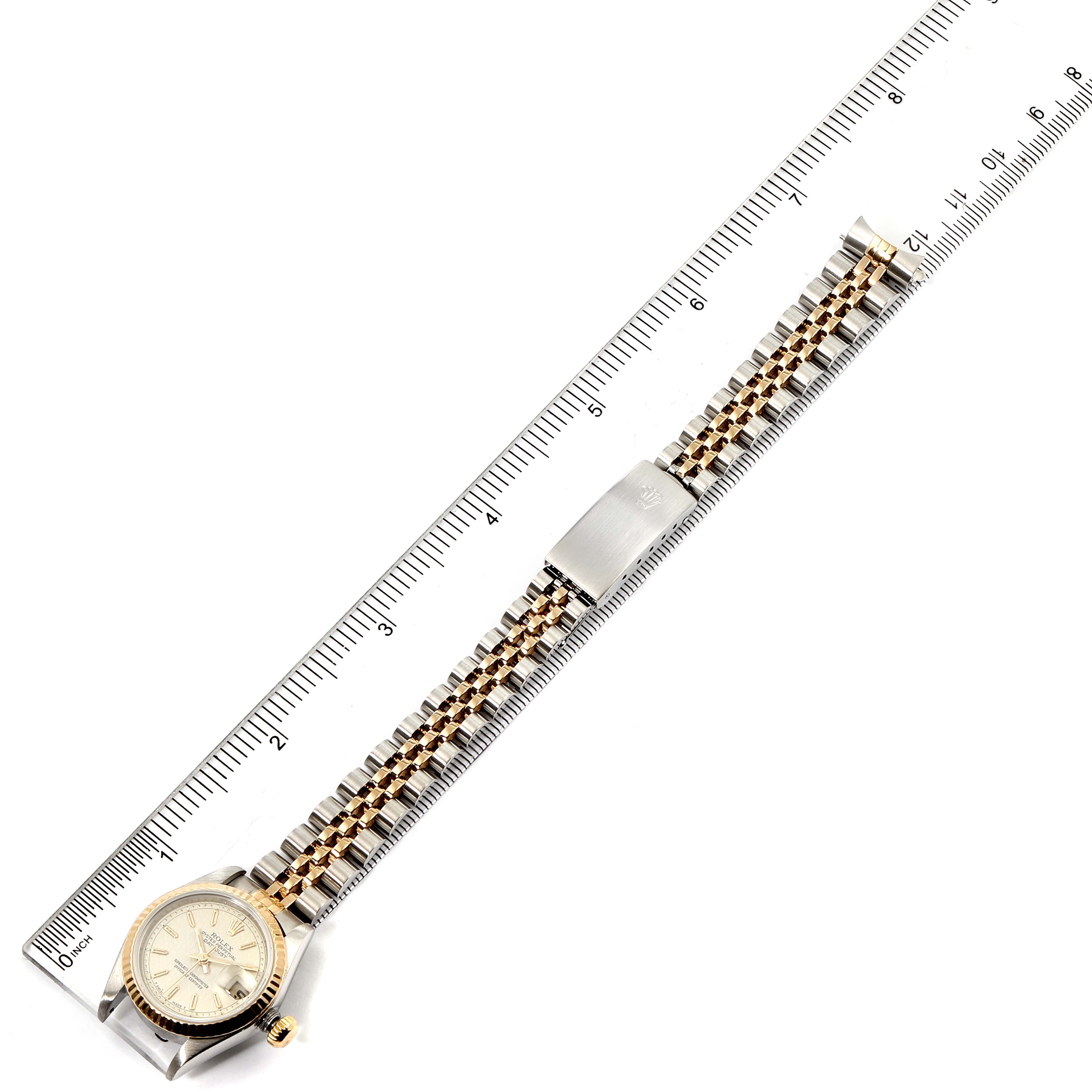 The Rolex Datejust 69173 Women's Steel and Gold (two tone) Beige Dial 69173 Women's Steel and Gold (two tone) Beige Dial watch is shown from a top-down angle, highlighting the dial, bezel, and two-tone bracelet alongside a ruler.