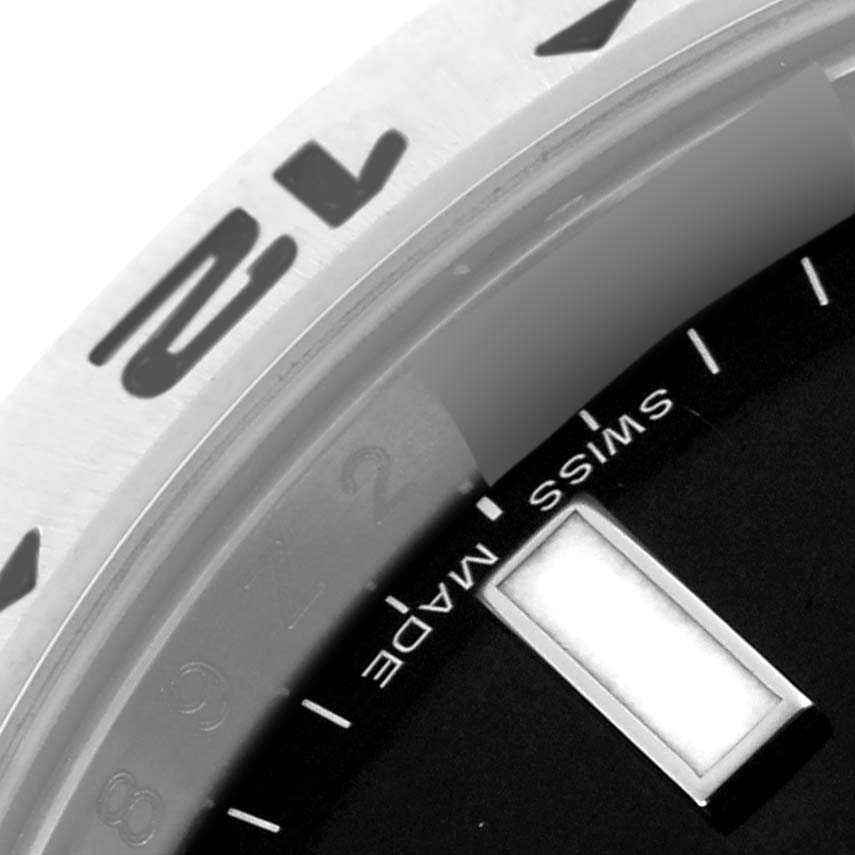 The image shows a close-up of the bezel and part of the dial of the Rolex Explorer 216570 Men's Stainless Steel Black Dial 216570 Men's Stainless Steel Black Dial watch.