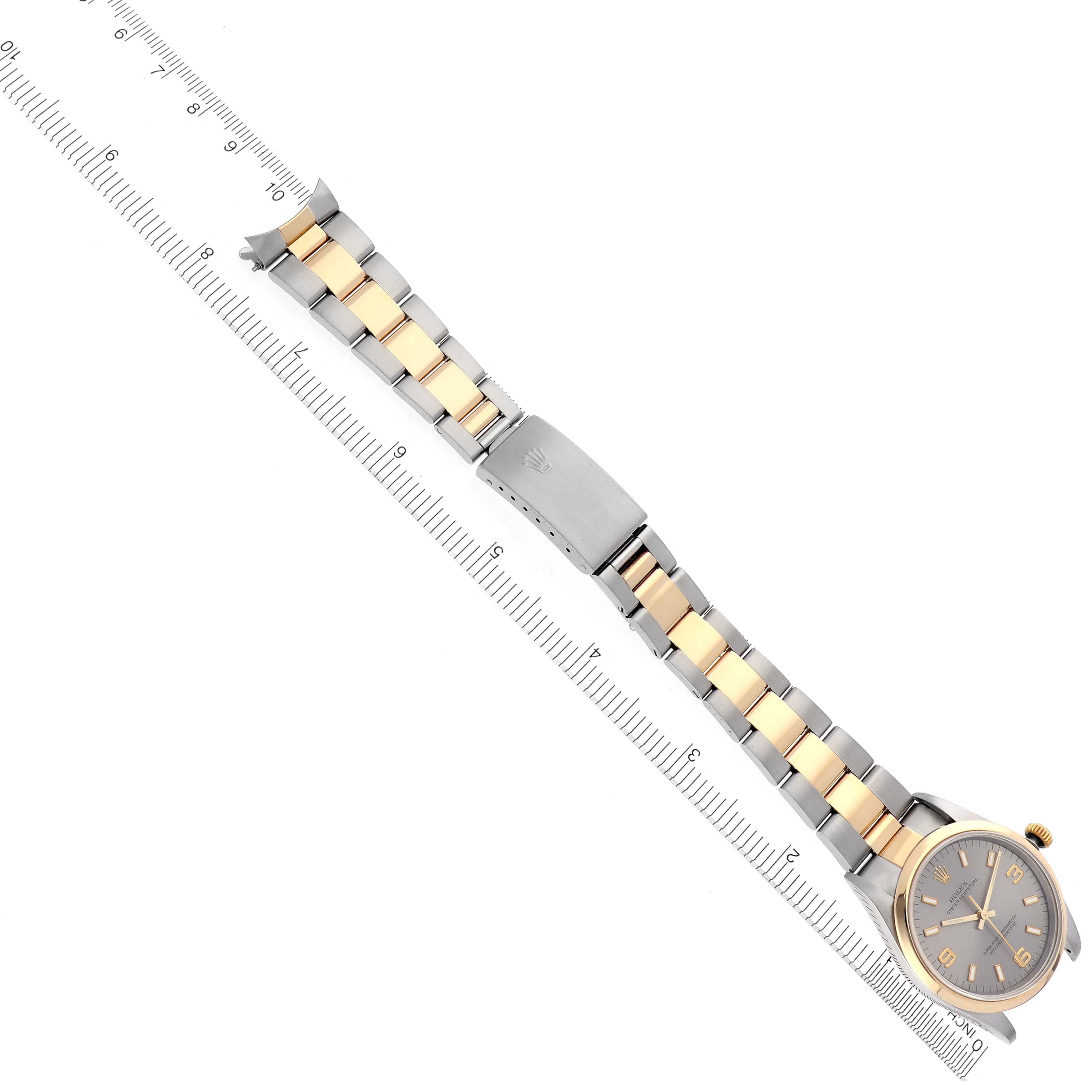 The Rolex Oyster Perpetual 14203 Men's Steel and Gold (two tone) Grey Dial 14203 Men's Steel and Gold (two tone) Grey Dial watch is shown from a top-down angle, displaying the bracelet and clasp alongside a ruler for scale.