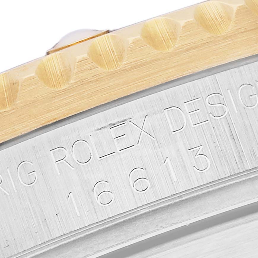 The image shows a close-up of the bezel edge and engraved case side of a Rolex Submariner 16613 Men's Steel and Gold (two tone) Black Dial 16613 Men's Steel and Gold (two tone) Black Dial.