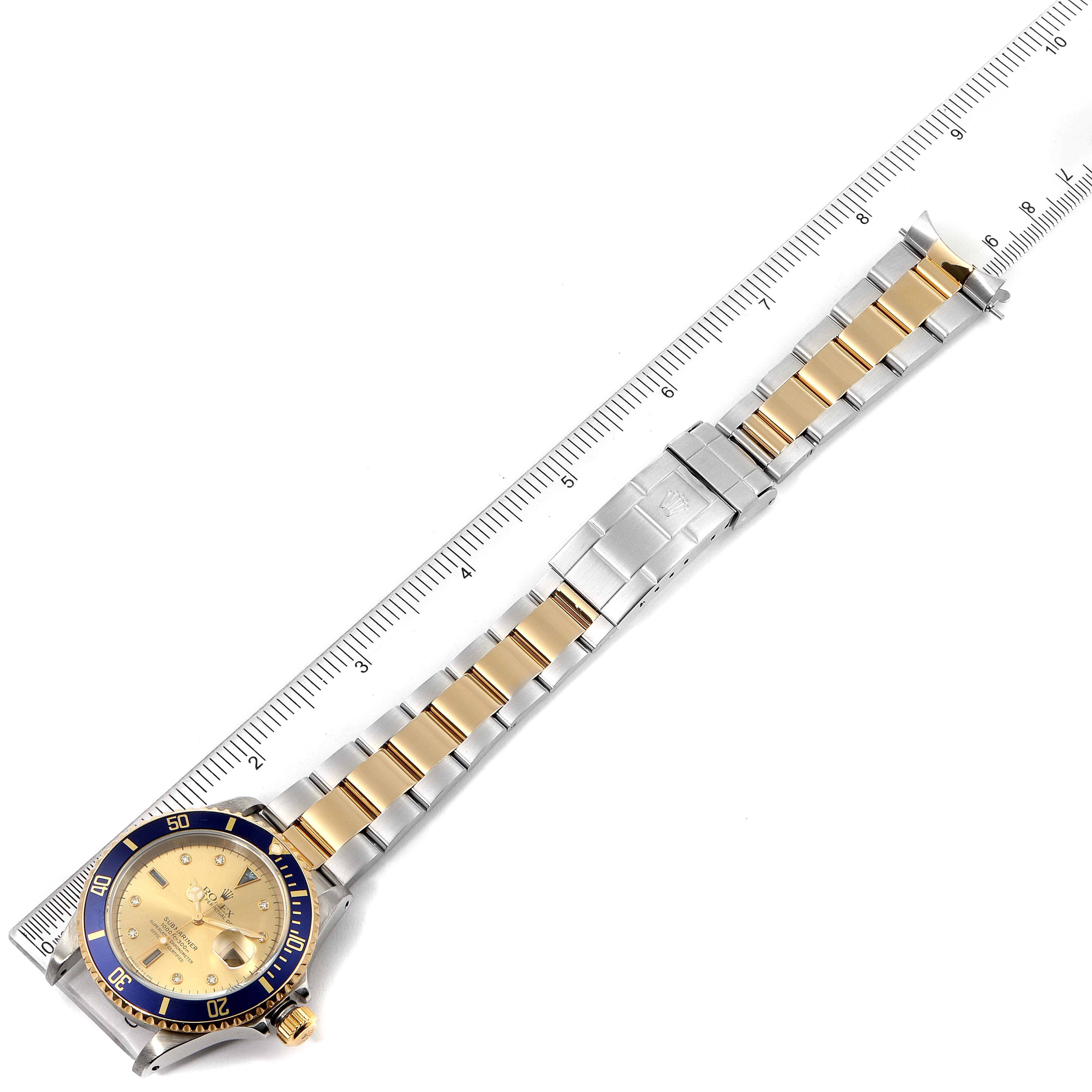 The image shows a Rolex Submariner 16613 Men's Steel and Gold (two tone) Champagne Dial 16613 Men's Steel and Gold (two tone) Champagne Dial watch laid flat beside a ruler, highlighting the bracelet and face.