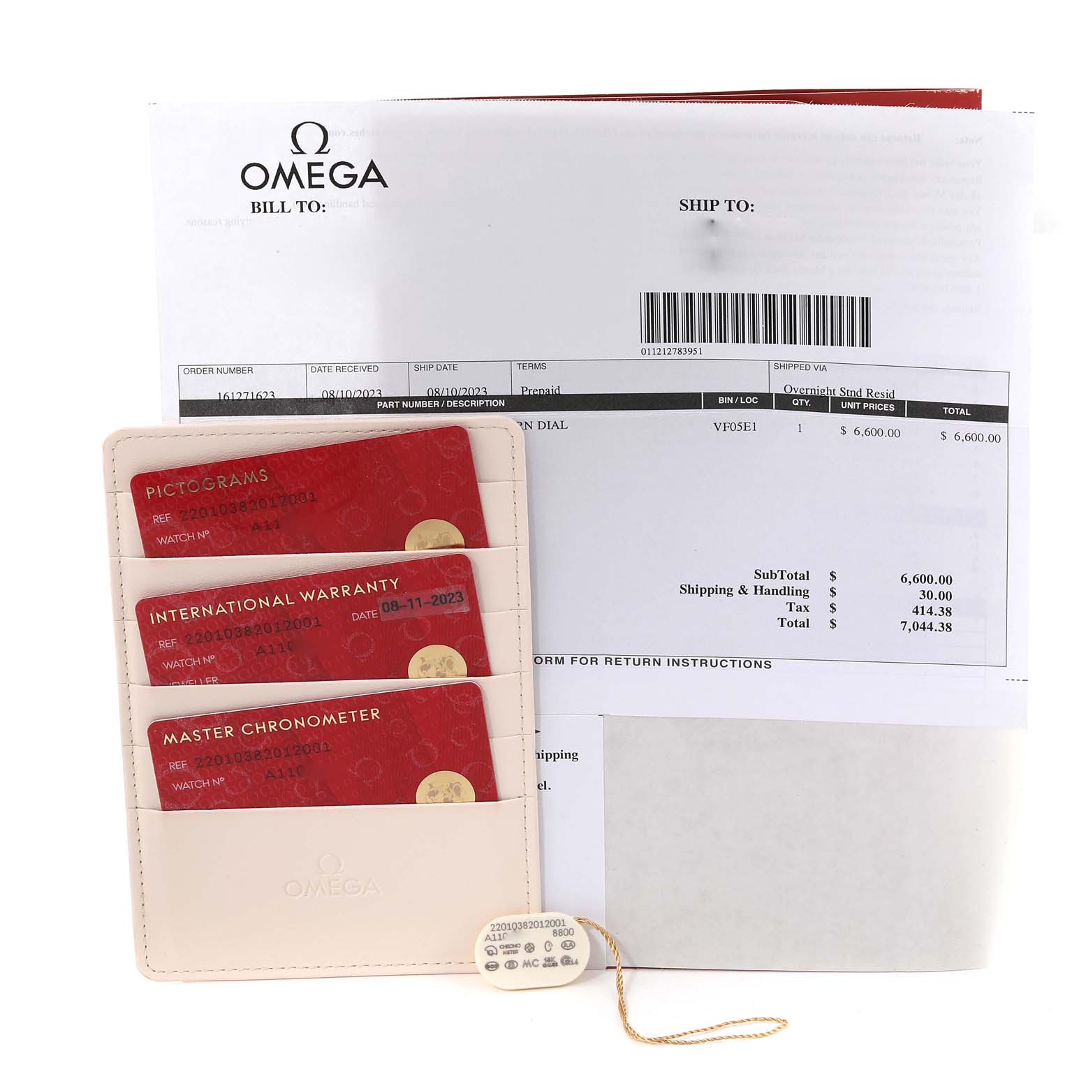 The image shows warranty cards, a tag, and paperwork for the Omega Aqua Terra 220.10.38.20.12.001 Men's Stainless Steel Pink Dial 220.10.38.20.12.001 Men's Stainless Steel Pink Dial watch, viewed from above.