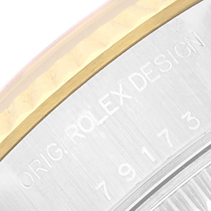 This close-up image shows the edge of the case back and part of the bezel of a Rolex Datejust 79173 Women's Steel and Gold (two tone) White Dial 79173 Women's Steel and Gold (two tone) White Dial watch, including engraved text.