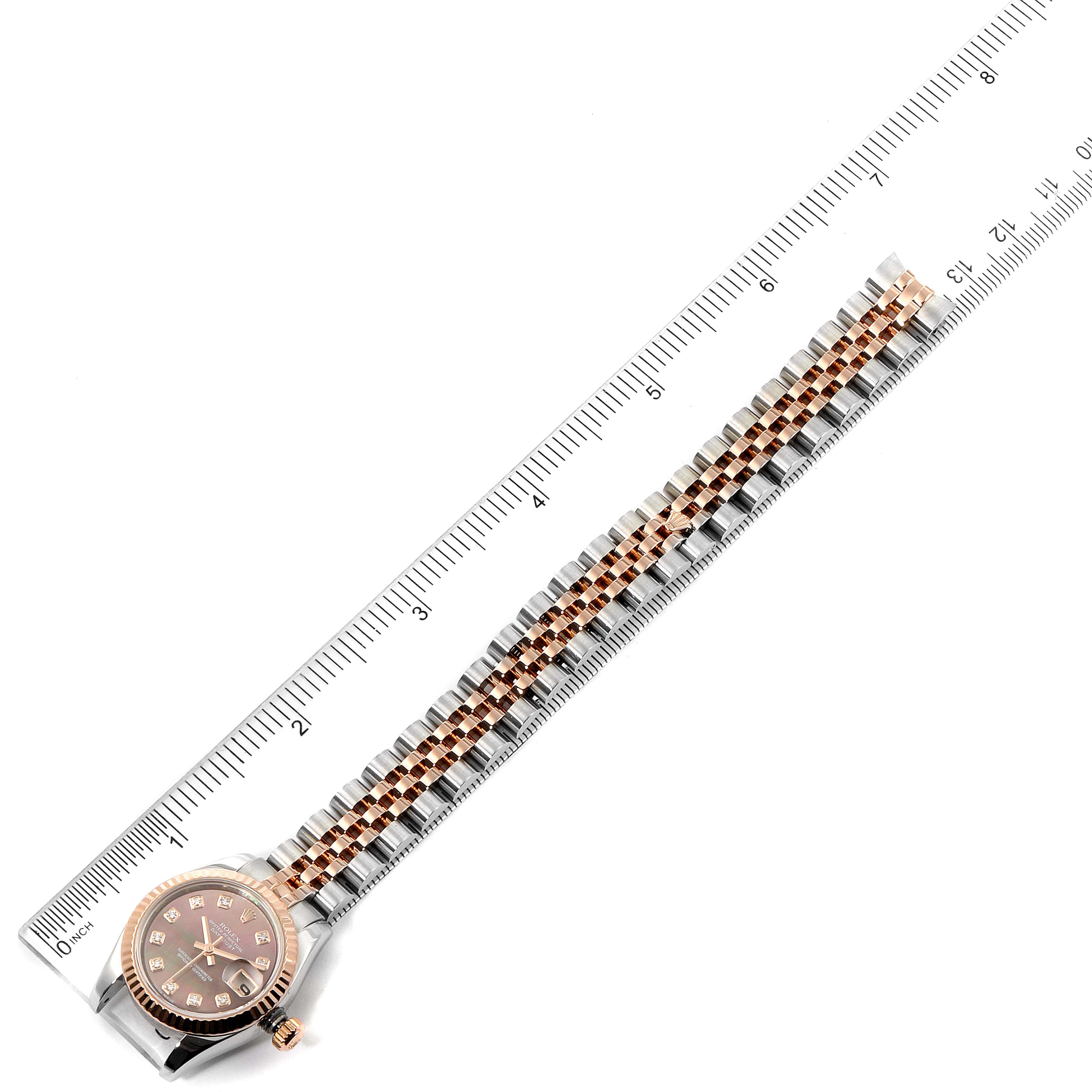 The Datejust Rolex watch is shown flat, with face and full bracelet visible, aligned next to a ruler for measurement.