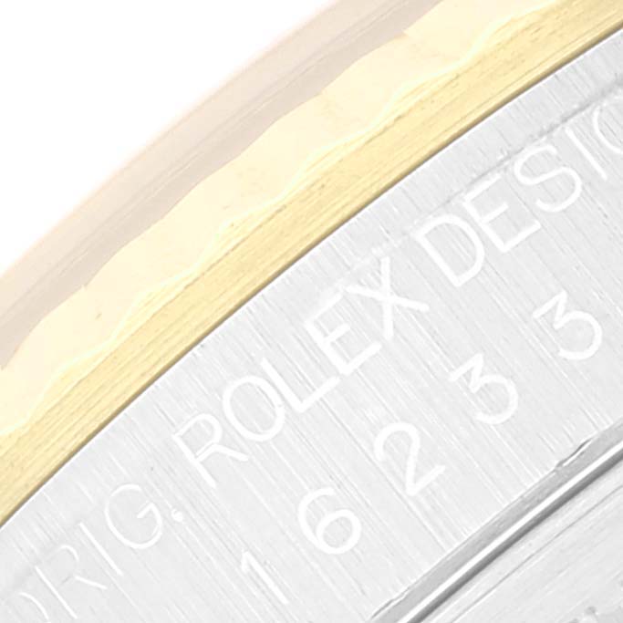 This close-up image shows the side of the Rolex Datejust 16233 Men's Steel and Gold (two tone) White Dial 16233 Men's Steel and Gold (two tone) White Dial watch case with part of the model number and "ROLEX DESIGN" engraving.