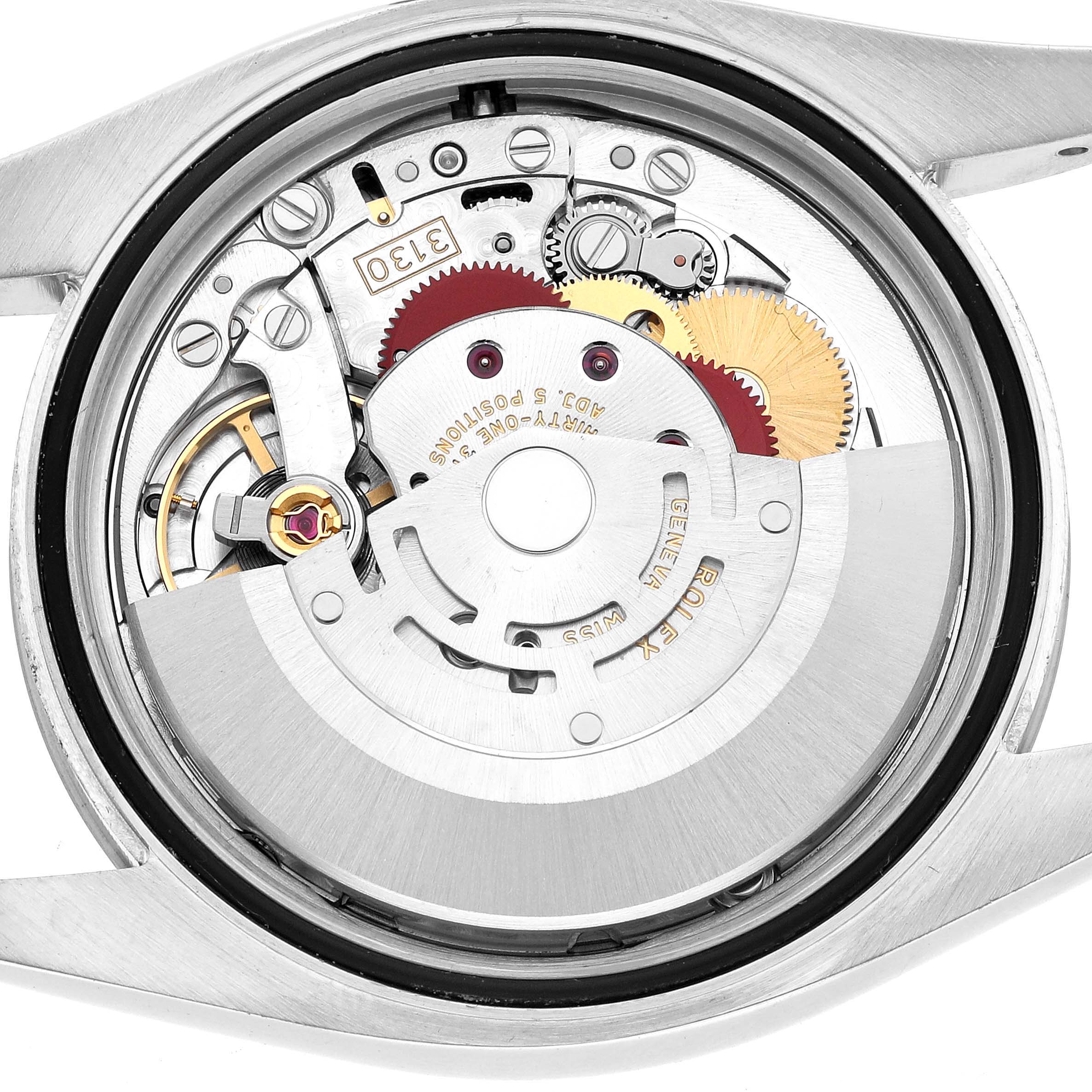 The image shows the internal mechanism of a Rolex Oyster Perpetual 116000 Men's Stainless Steel Silver Dial watch from a rear view, highlighting gears and movement parts.