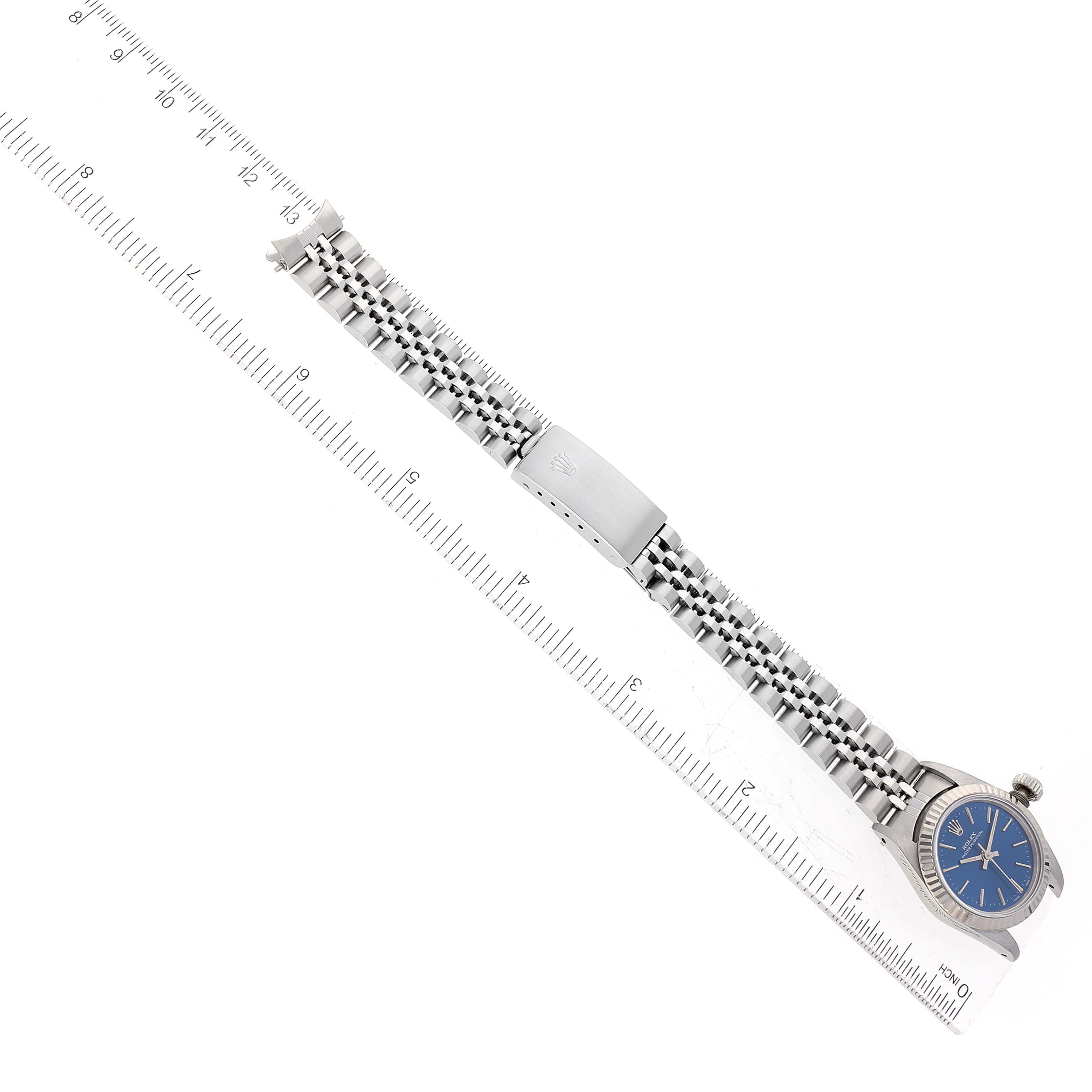 The image shows a Rolex Oyster Perpetual 67194 Women's Stainless Steel Blue Dial 67194 Women's Stainless Steel Blue Dial watch with a blue dial, positioned alongside a ruler to measure its length.