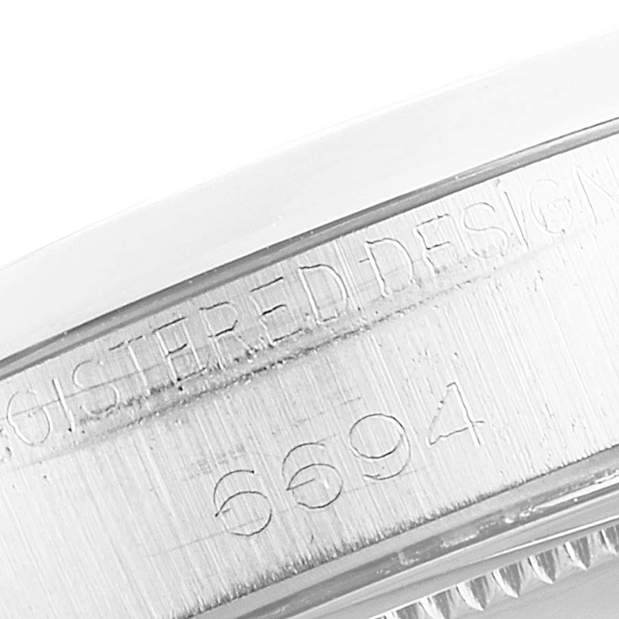 This image shows an angled close-up of the engraved serial number and "Registered Design" on a Rolex Vintage Collection 6694 Men's Stainless Steel Silver Dial 6694 Men's Stainless Steel Silver Dial model.