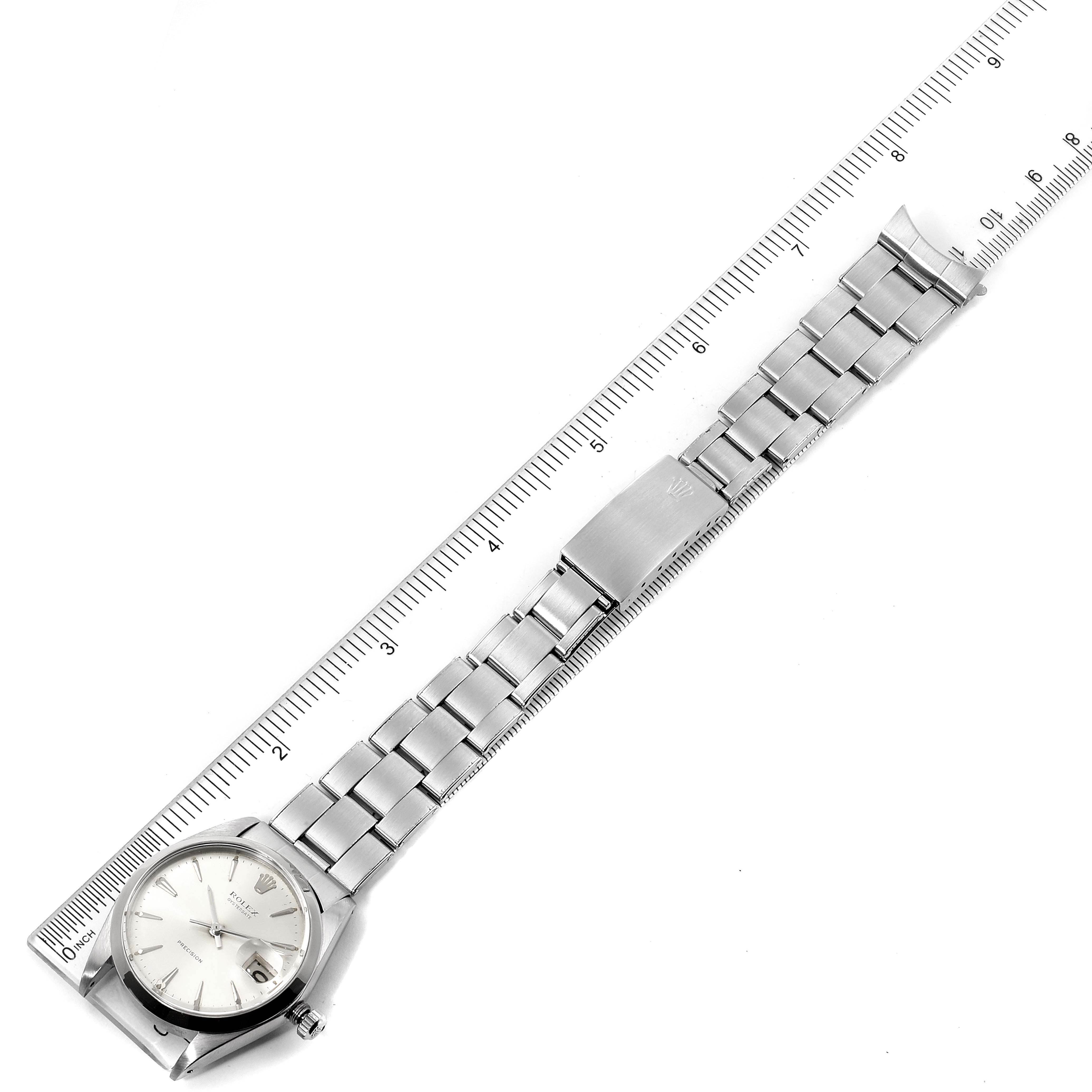 The Vintage Collection Rolex watch is photographed from a top-down angle, showing the face, bracelet, and clasp, alongside a measuring ruler.