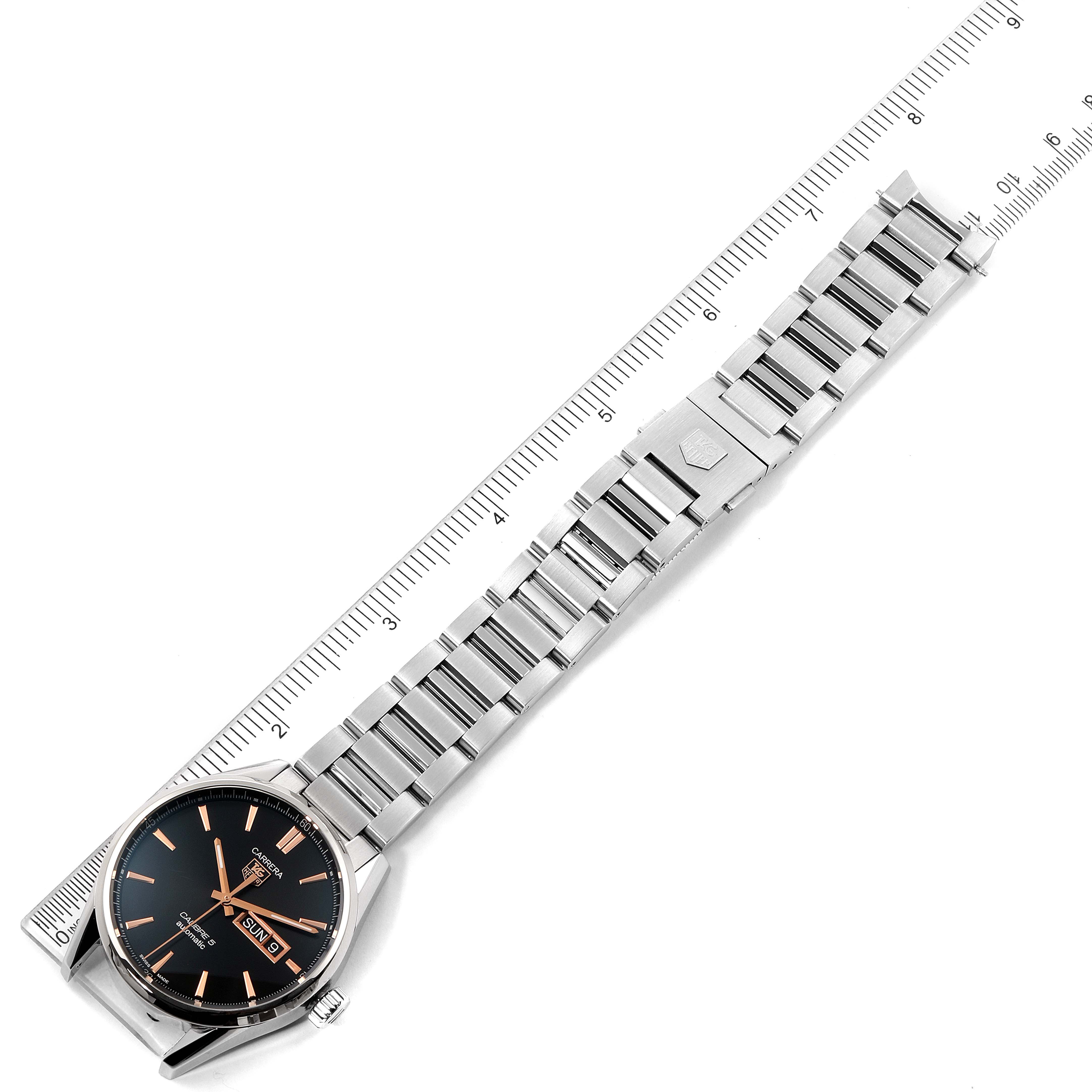 This image shows a Tag Heuer Carrera WAR201C.BA0723 Men
s Stainless Steel Black Dial WAR201C.BA0723 Men
s Stainless Steel Black Dial model watch laying flat with its stainless steel band extended, alongside a ruler.