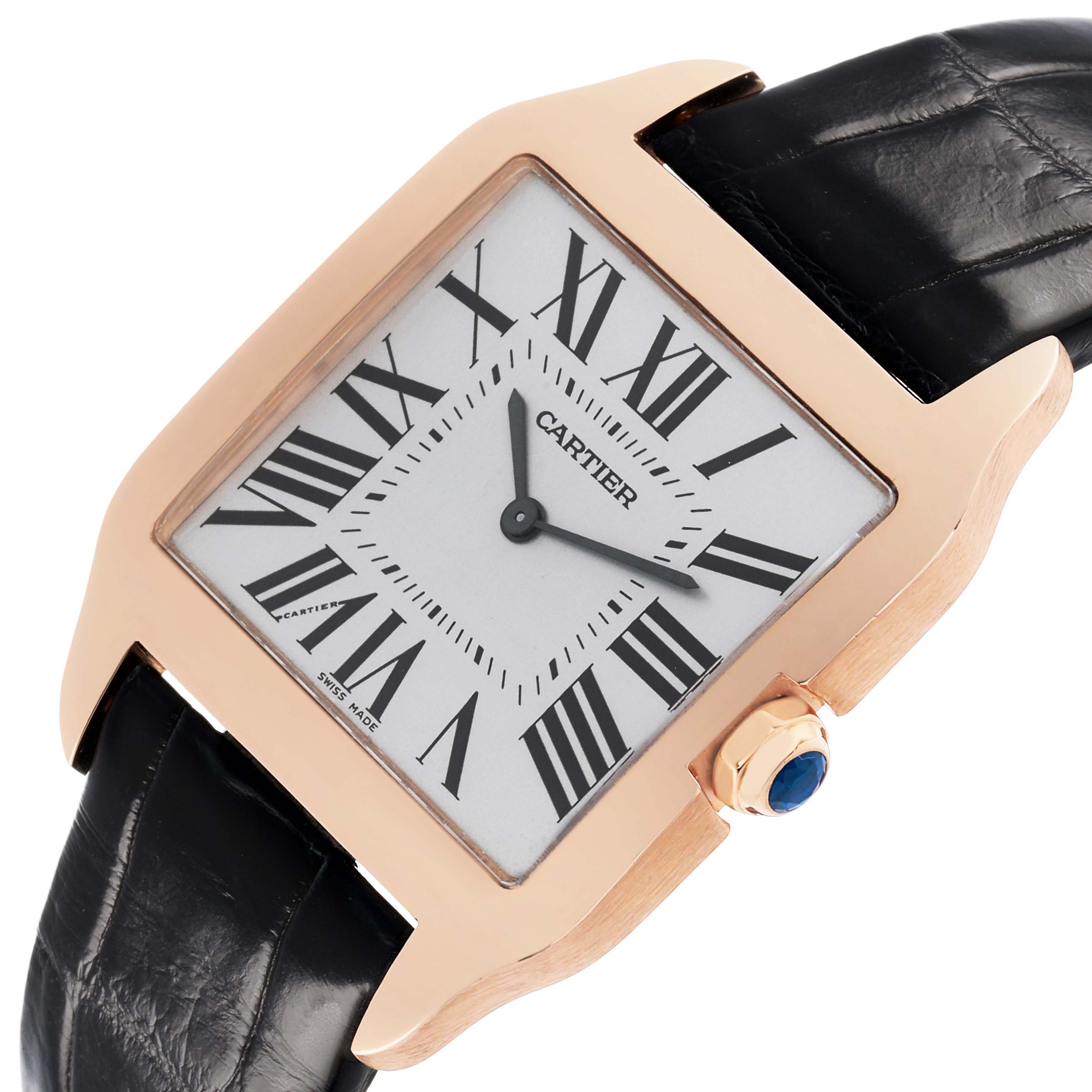 The Cartier Santos Dumont W2006951 Men's Rose Gold Silver Dial watch is shown from a front angle, highlighting its square dial, black leather strap, and blue cabochon crown.