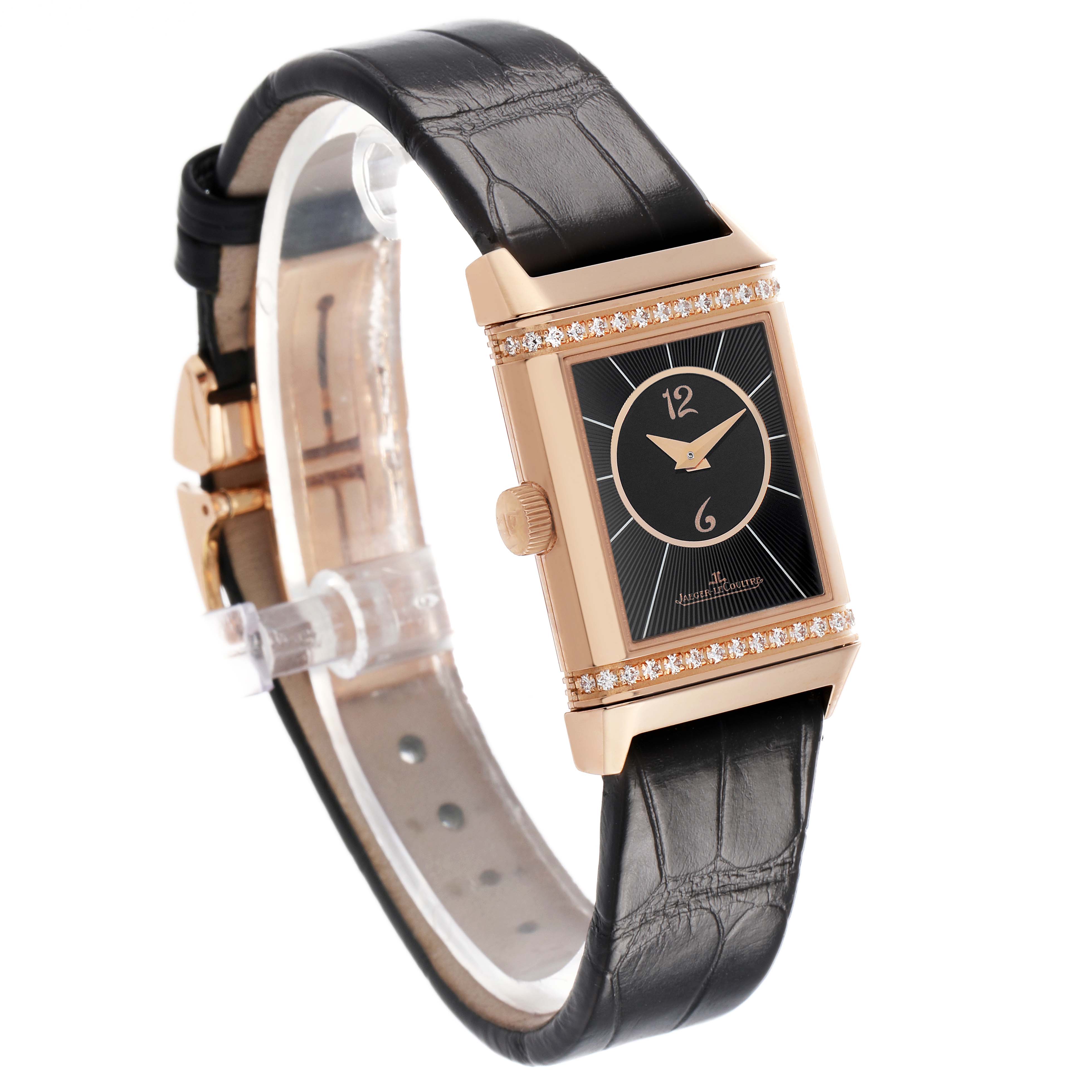The Jaeger-LeCoultre Reverso watch is shown at an angle highlighting its rectangular dial, bezel with diamonds, crown, and black leather strap.