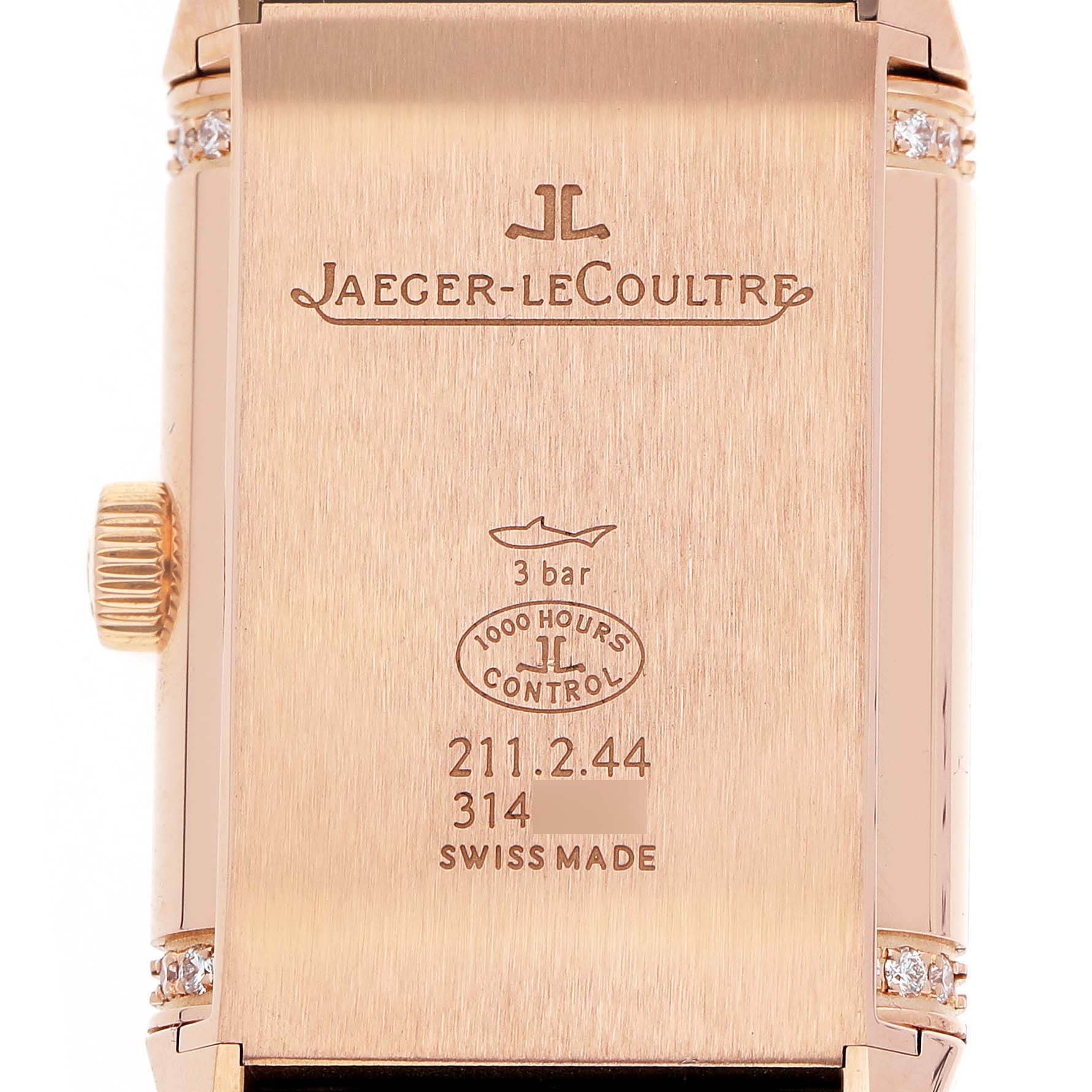 The image shows the back of a Jaeger-LeCoultre Reverso watch, featuring inscriptions and the side crown.