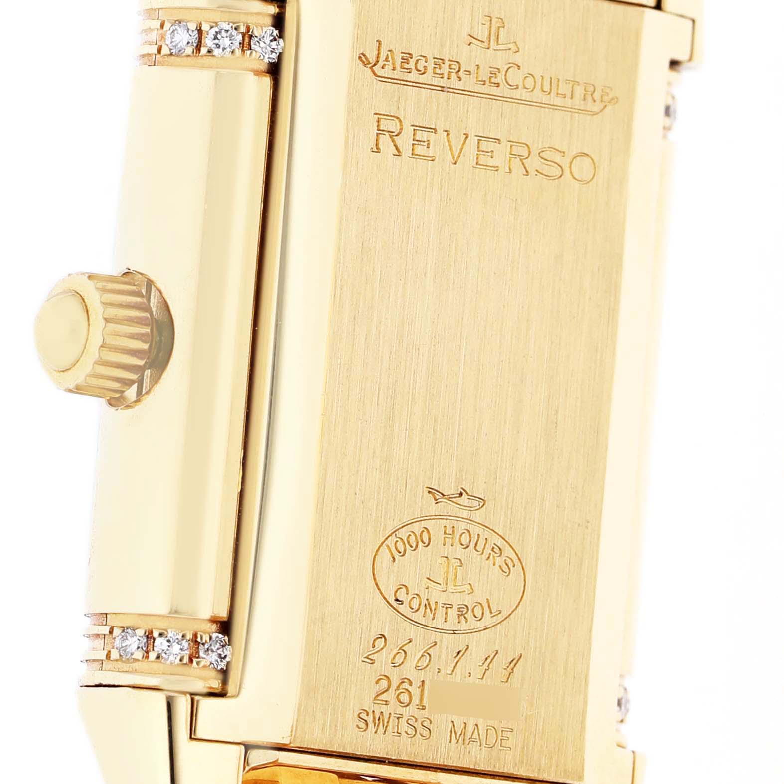 The image shows the back of a Jaeger-LeCoultre Reverso watch, highlighting the engraving, crown, and diamond-set details.