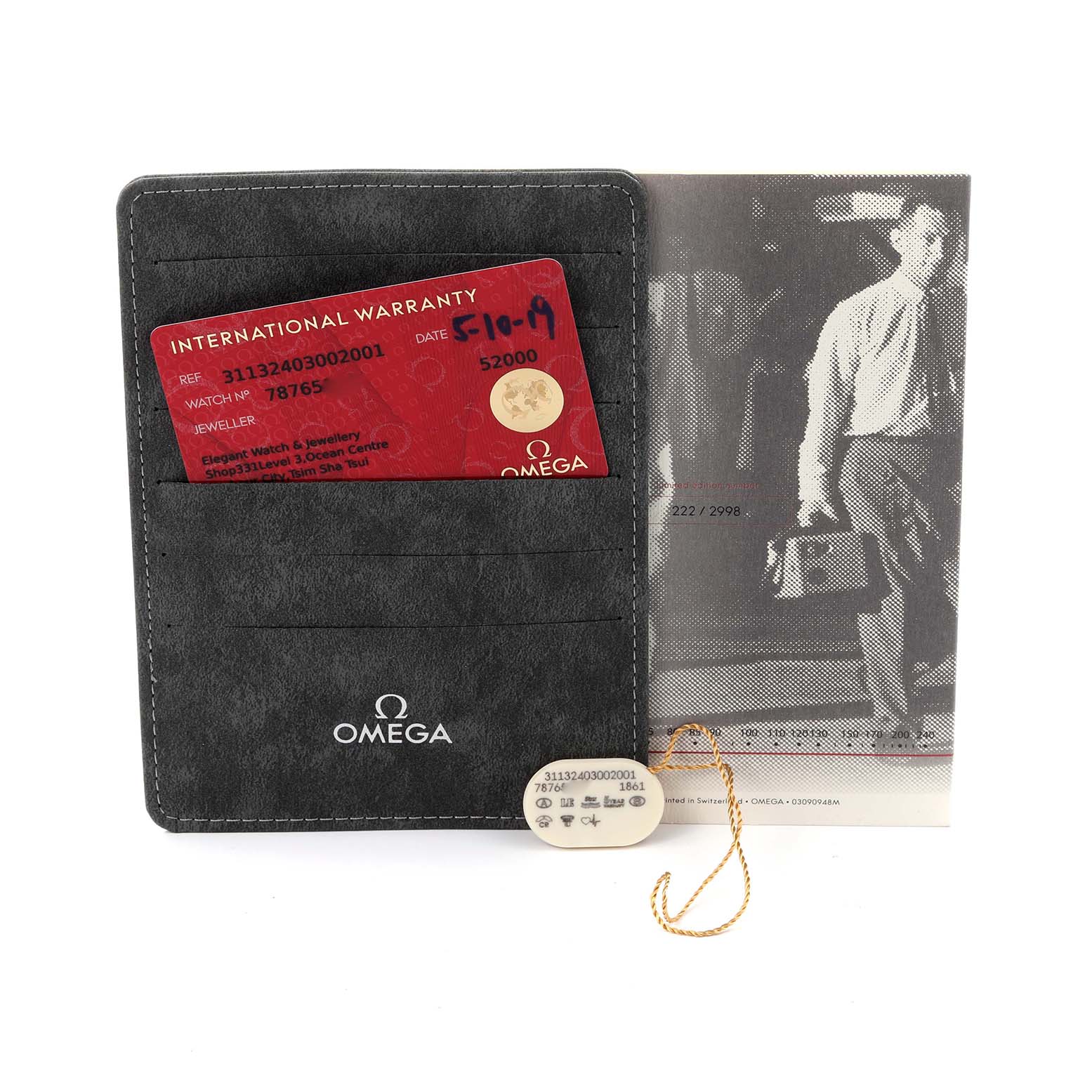 The image shows an Omega Speedmaster 311.32.40.30.02.001 Men's Stainless Steel Silver Dial 311.32.40.30.02.001 Men's Stainless Steel Silver Dial warranty card, booklet, and a tag from the front angle.