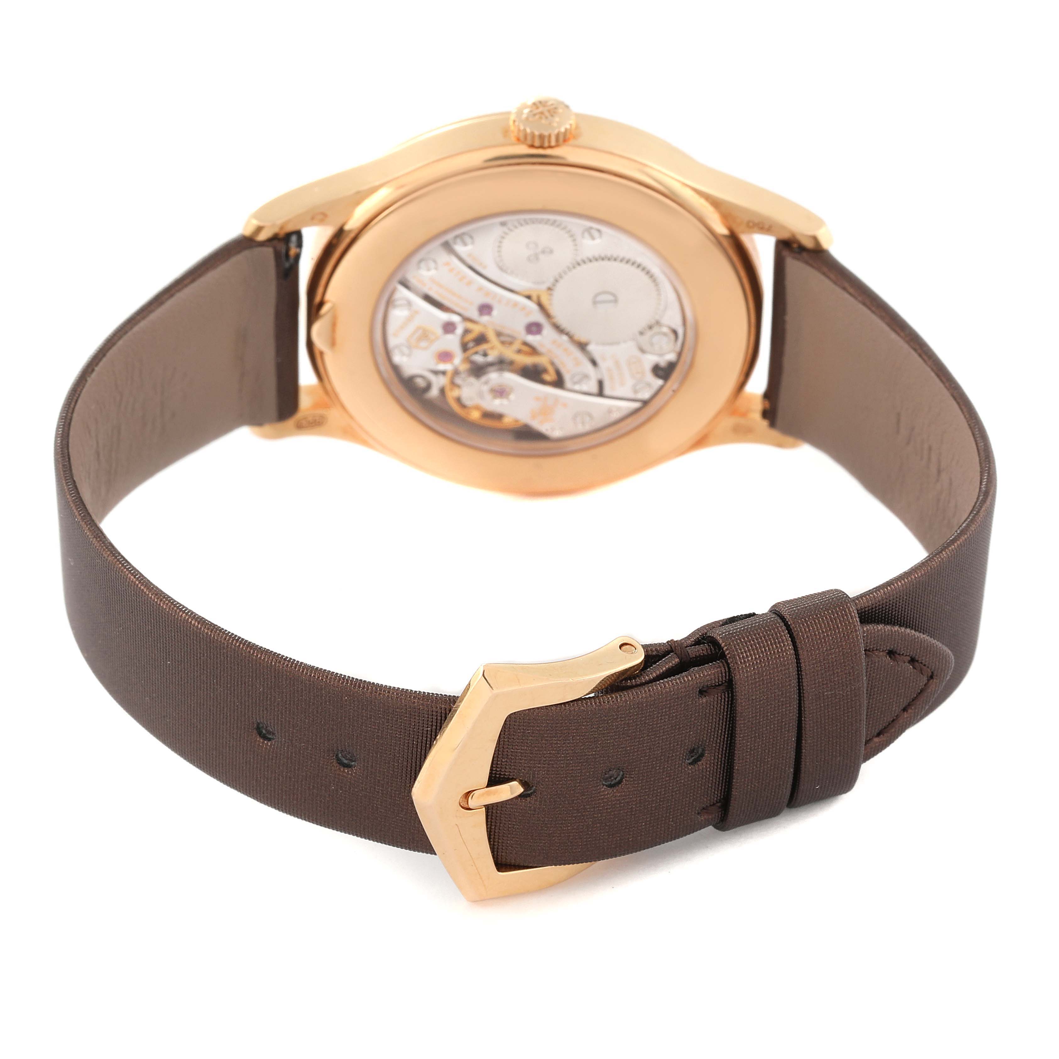 The image shows the back view of a Patek Philippe Calatrava 4897R-001 Women's Rose Gold Brown Dial 4897R-001 Women's Rose Gold Brown Dial watch, highlighting the movement and brown leather strap with a gold buckle.