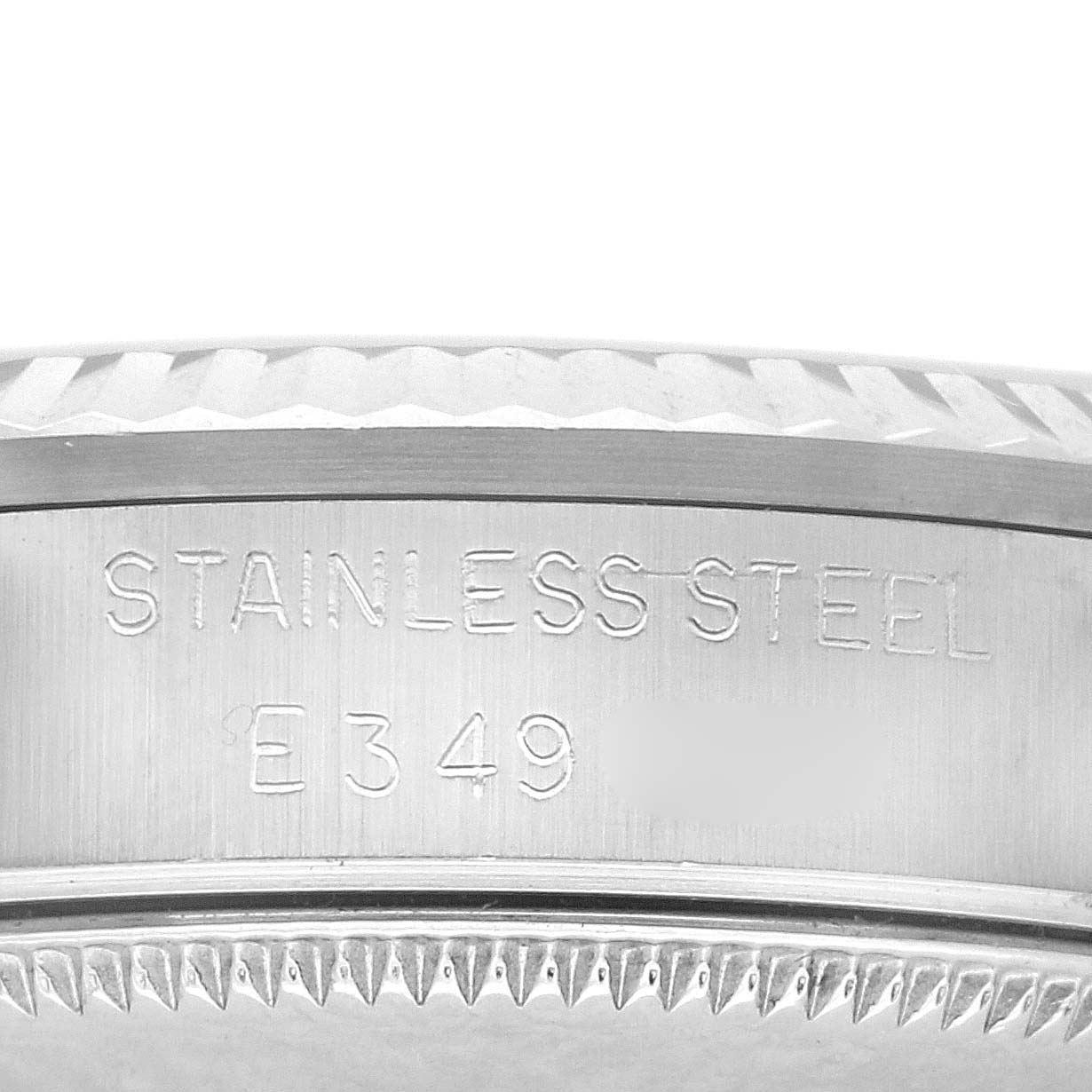 The image shows a close-up of a Rolex Mid-Size 68274 Women's Stainless Steel Silver Dial 68274 Women's Stainless Steel Silver Dial watch bezel with "STAINLESS STEEL" and a serial number engraved on it.