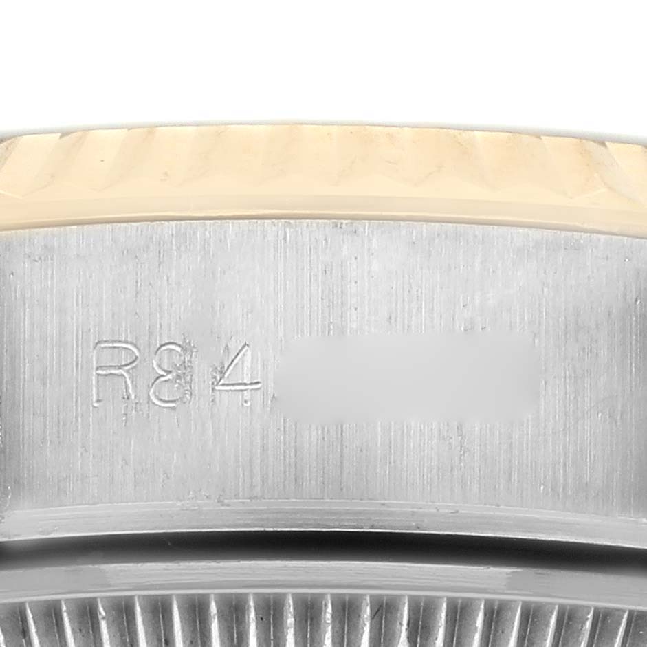 The image shows a close-up of the side of a Rolex Datejust 69173 Women's Steel and Gold (two tone) Champagne Dial 69173 Women's Steel and Gold (two tone) Champagne Dial watch, featuring part of the bezel and engraved serial numbers.