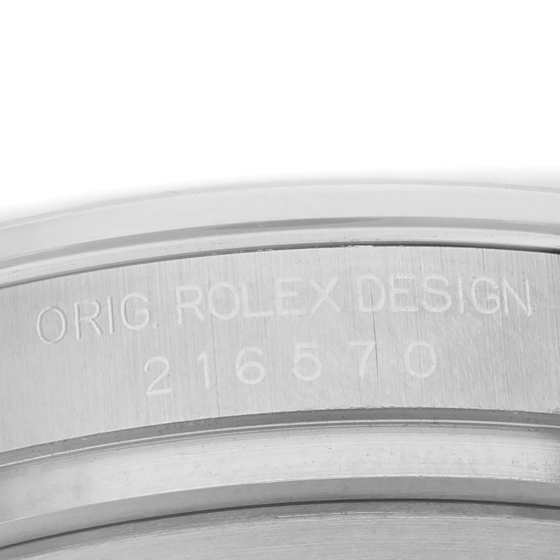 The image shows the side of a Rolex Oyster Perpetual 216570 Men's Stainless Steel Black Dial, highlighting the engraved inscription on the watch case.