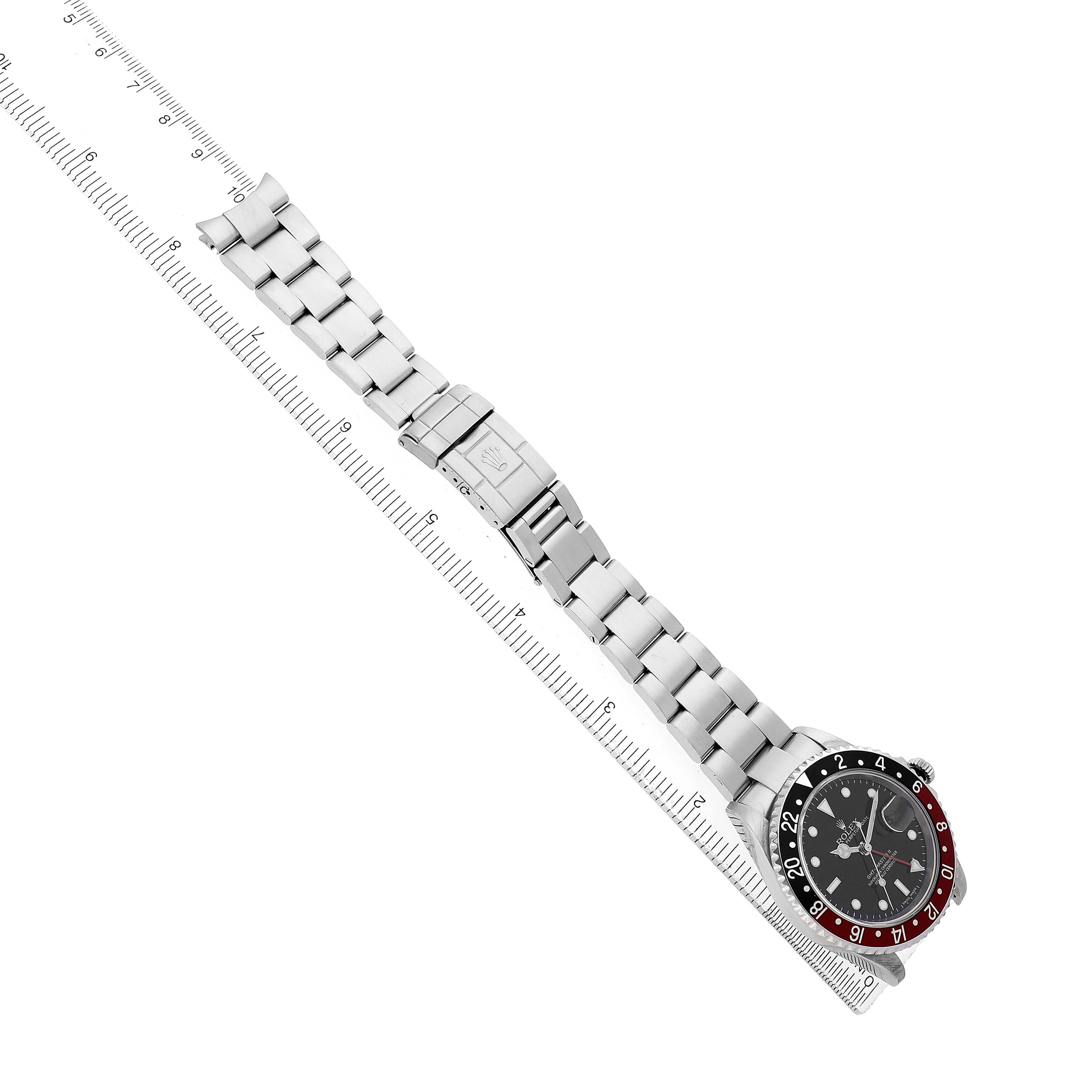 The Rolex GMT-Master 16710 Men's Stainless Steel Black Dial watch is shown from a top-down angle, displaying the face, bezel, and full bracelet with a ruler beside it.