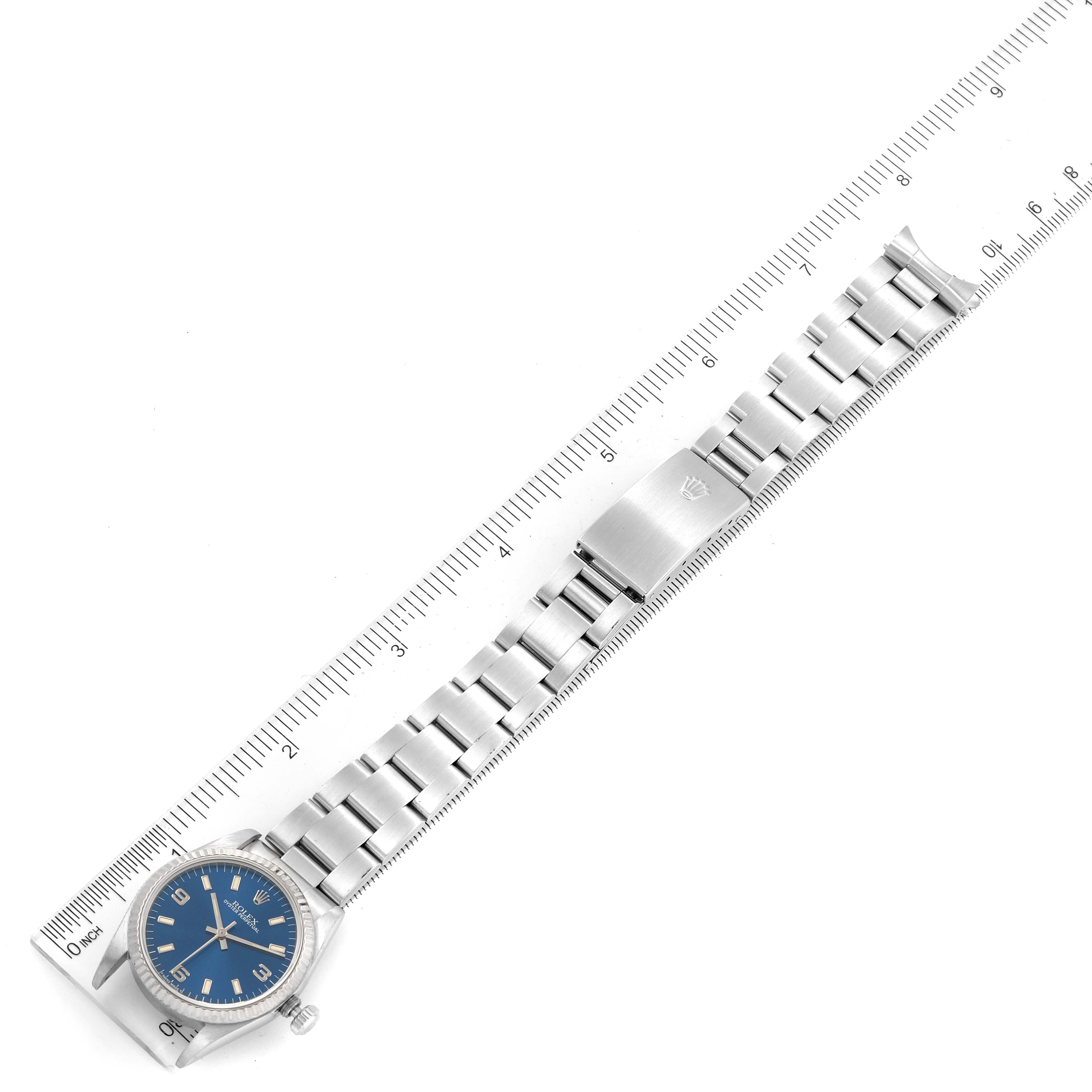 The image shows a top view of a Mid-Size Rolex watch with a blue dial and stainless steel bracelet placed along a ruler.