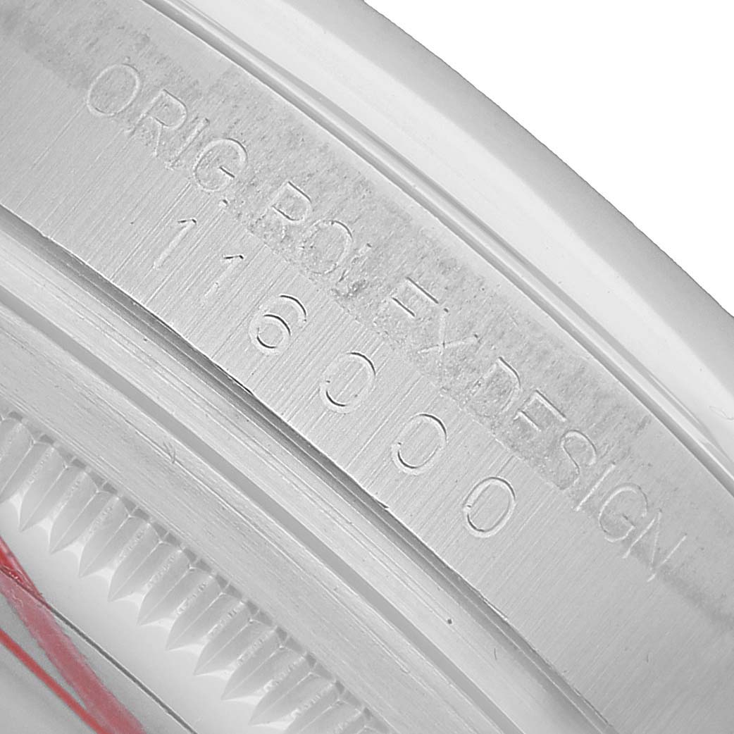 The image shows a close-up of the engraved bezel of a Rolex Oyster Perpetual 116000 Men's Stainless Steel Silver Dial watch, highlighting the model number.