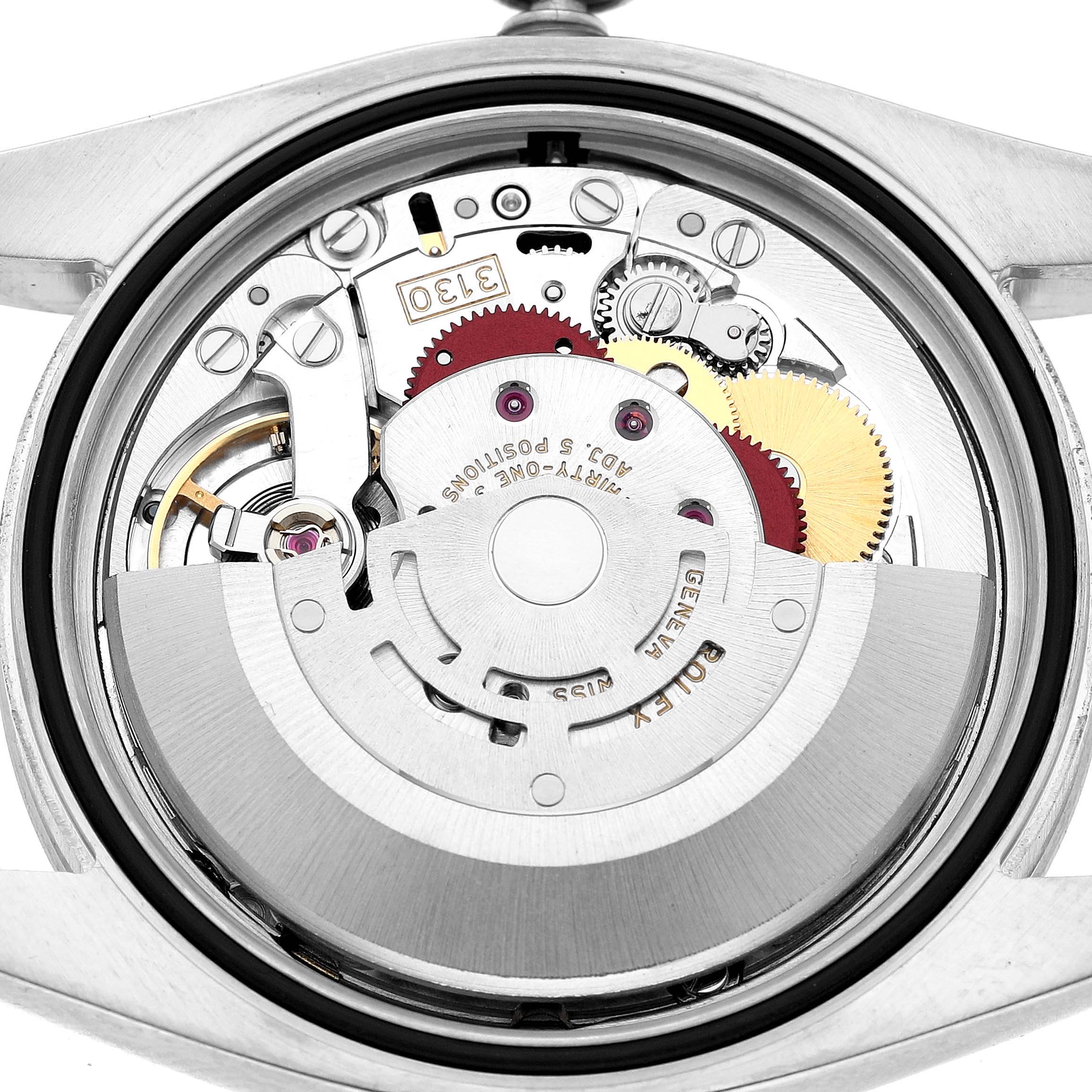 The image shows the movement of a Rolex Oyster Perpetual 116000 Men's Stainless Steel Blue Dial watch from a back view, highlighting gears and the rotor.