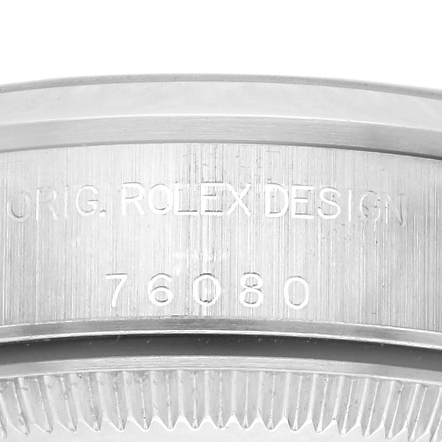 The image shows a close-up of the engraved side of a Rolex Oyster Perpetual 76080 Women's Stainless Steel Pink Dial 76080 Women's Stainless Steel Pink Dial bezel, highlighting its serial number and design.